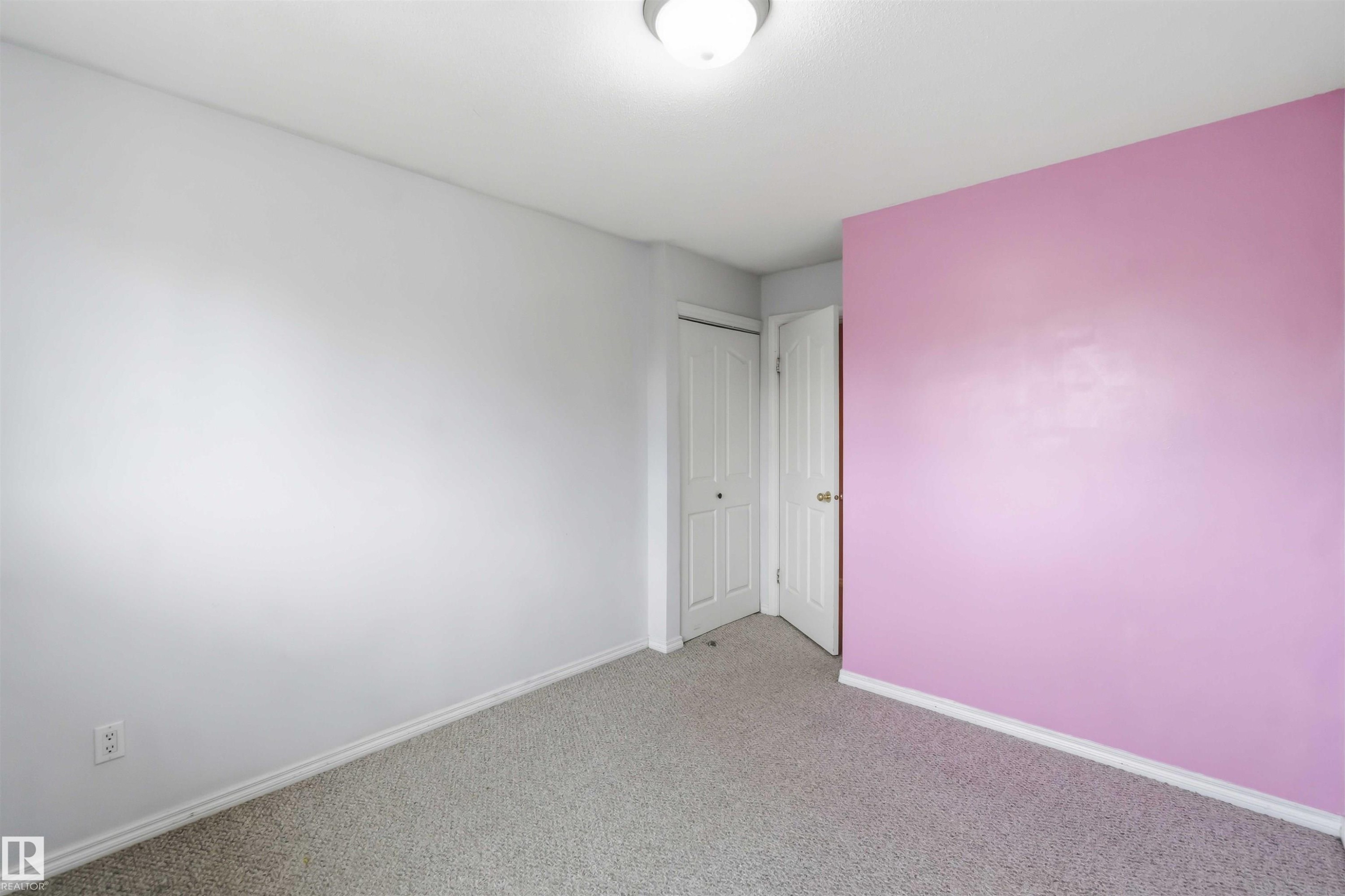 Interior room featuring light gray walls, a single pink accent wall, and a gray carpeted floor - 17325 85 Avenue Nw, Edmonton, AB