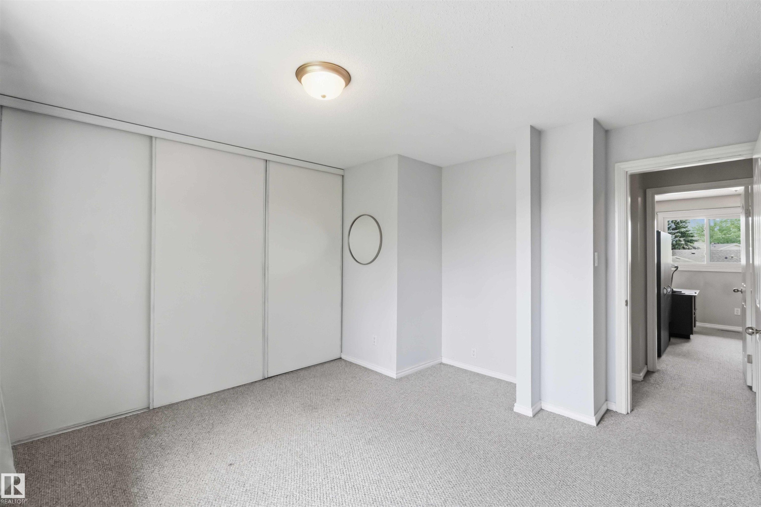 Carpeted room with a ceiling-mounted light fixture and sliding closet doors - 17325 85 Avenue Nw, Edmonton, AB