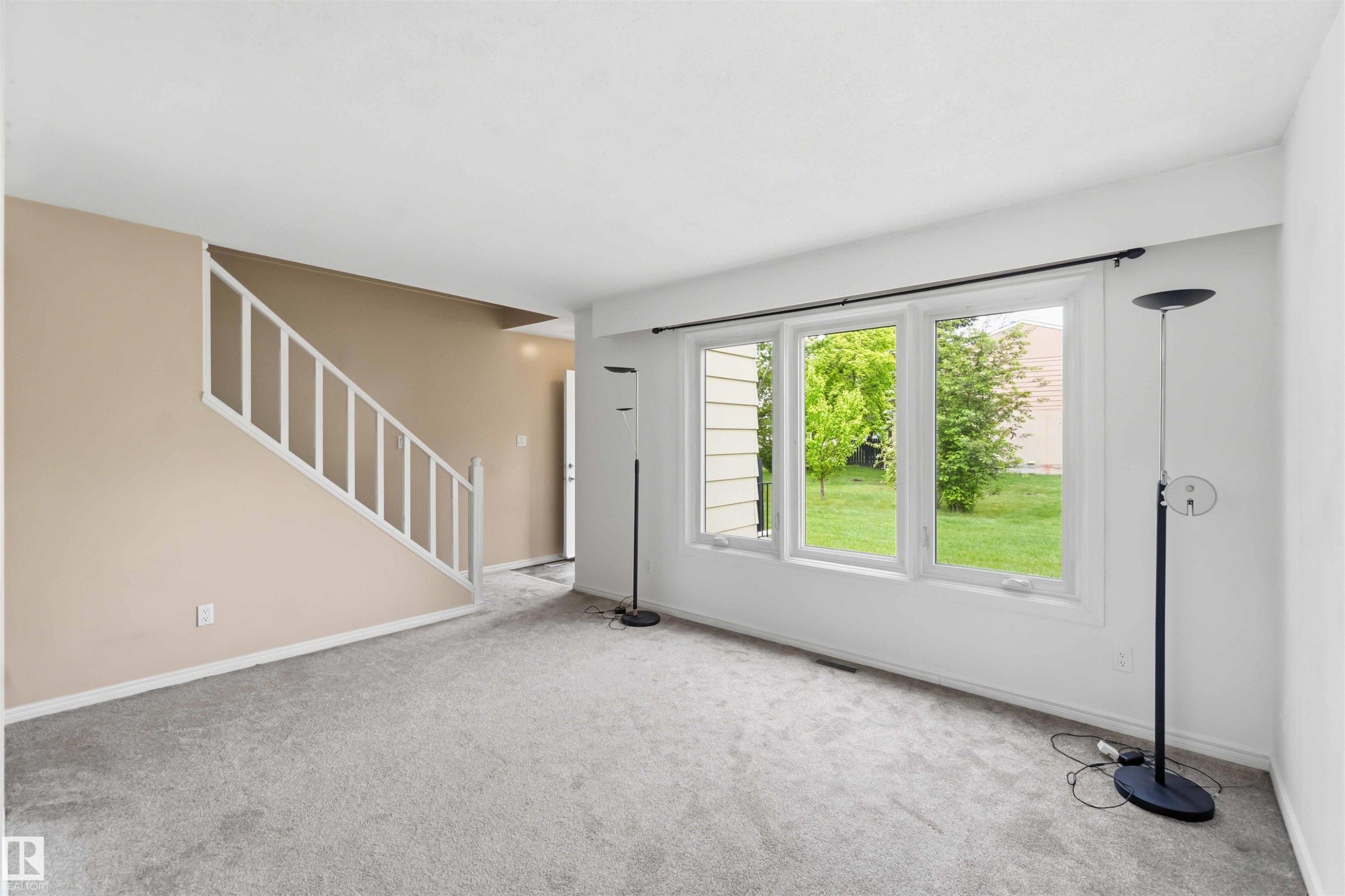 Living area featuring a three-panel window overlooking green landscaping - 17325 85 Avenue Nw, Edmonton, AB