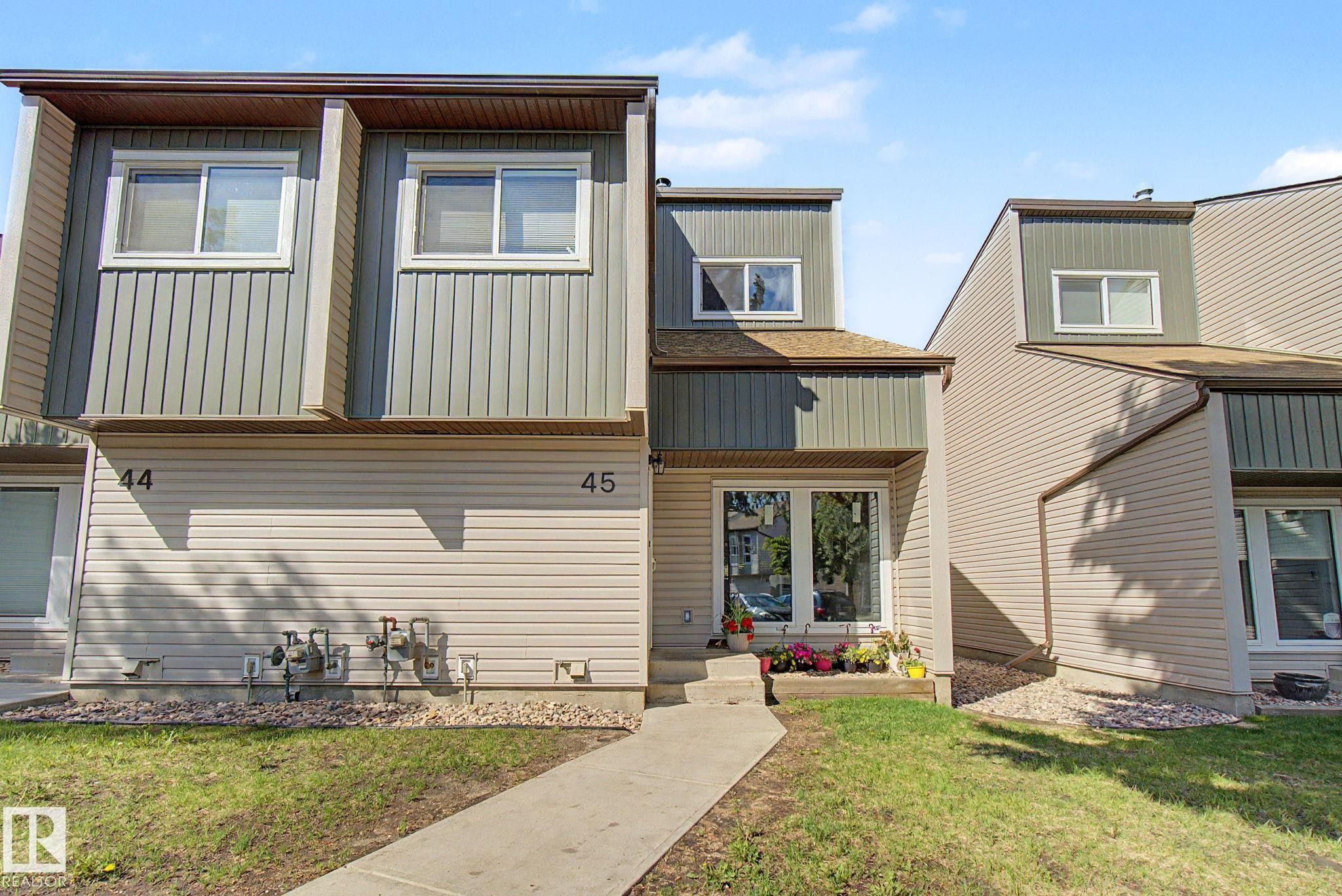 Townhome exterior featuring multi-toned siding, white-framed windows, and a concrete walkway - #45 2020 105 St Nw, Edmonton, AB - Outdoor
