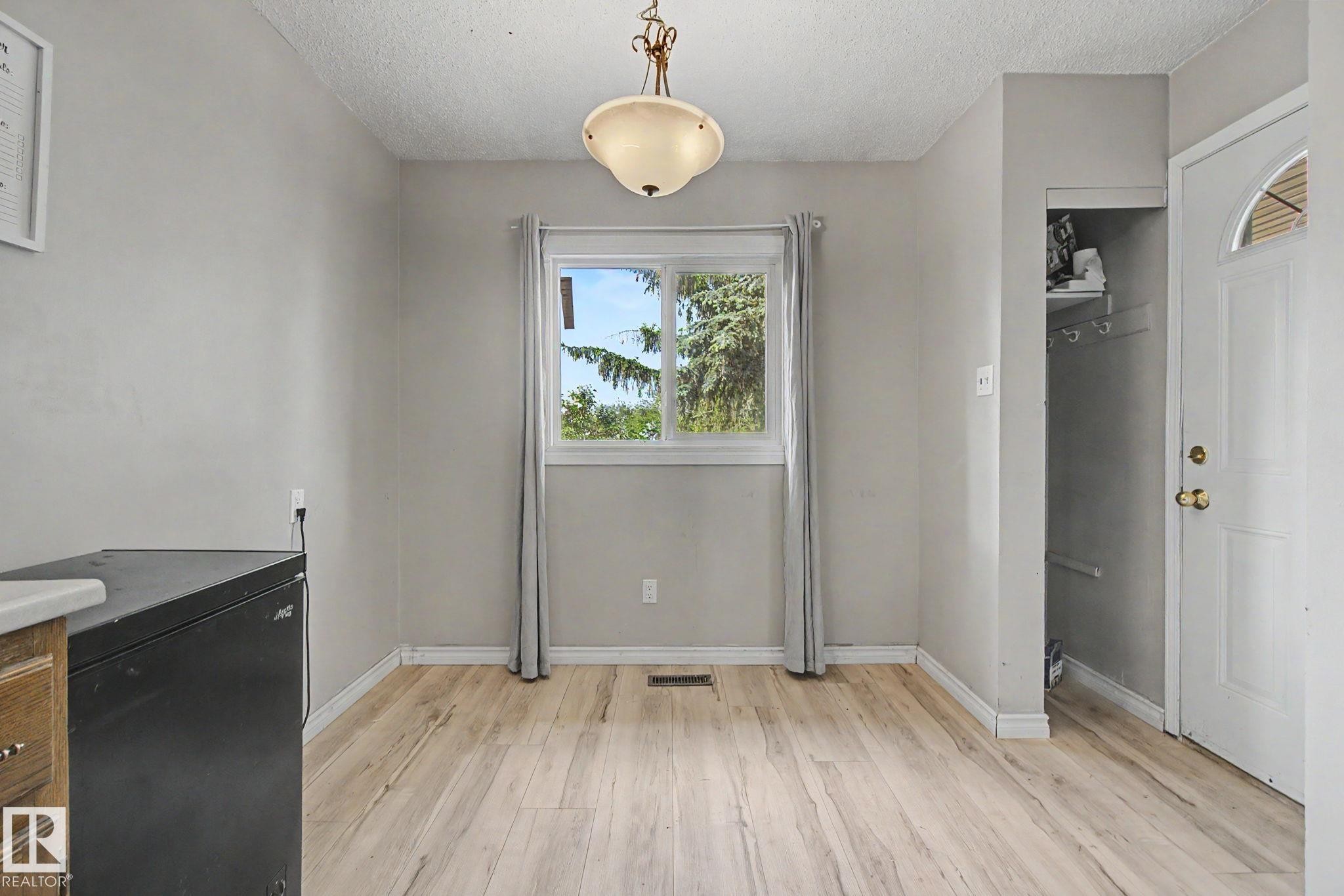 Bright interior space featuring wood-finish flooring, a central window with white trim, and light gray wall finishes - #45 2020 105 St Nw, Edmonton, AB - Indoor Photo Showing Other Room