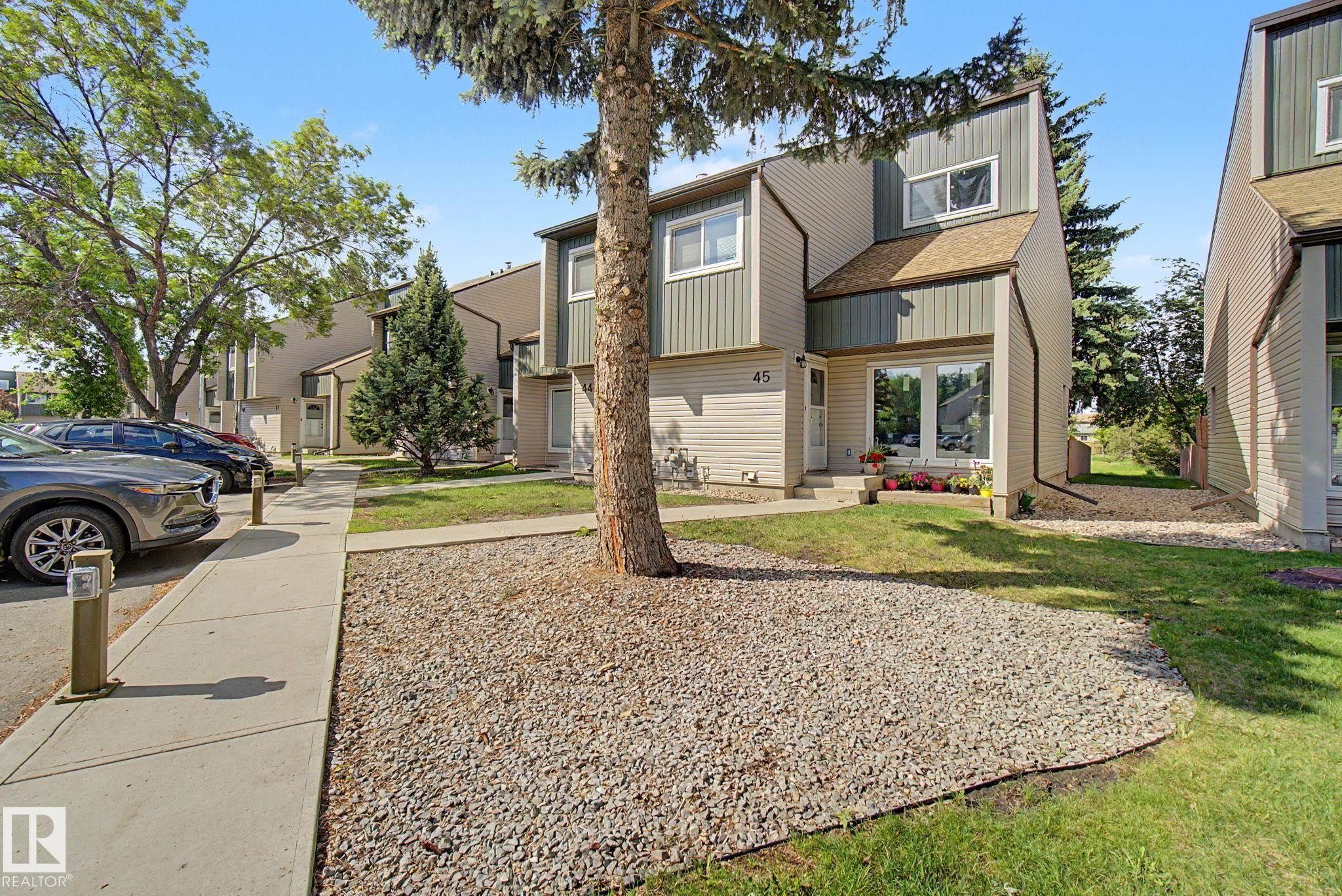 Contemporary townhome exterior featuring multi-toned siding, a distinct roofline, a prominent front entrance with large glass panels, and a concrete pathway - #45 2020 105 St Nw, Edmonton, AB - Outdoor