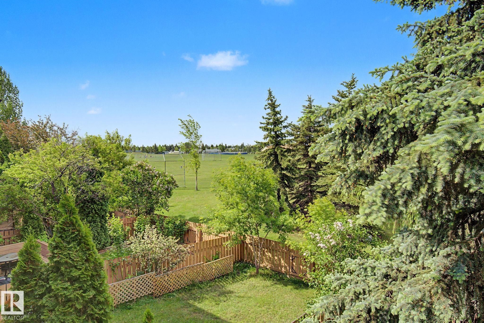 Expansive backyard featuring a manicured lawn, established landscaping, and a wooden fence - #45 2020 105 St Nw, Edmonton, AB - Outdoor