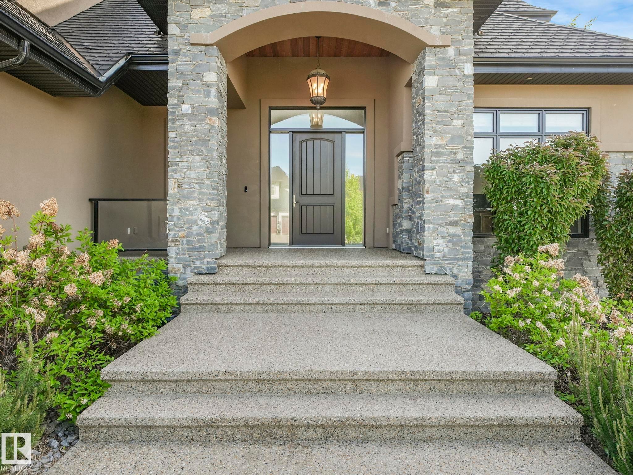 Stately entrance featuring a dark paneled door with sidelight, stone veneer columns, and an arched portico - 2807 Wheaton Drive, Edmonton, AB