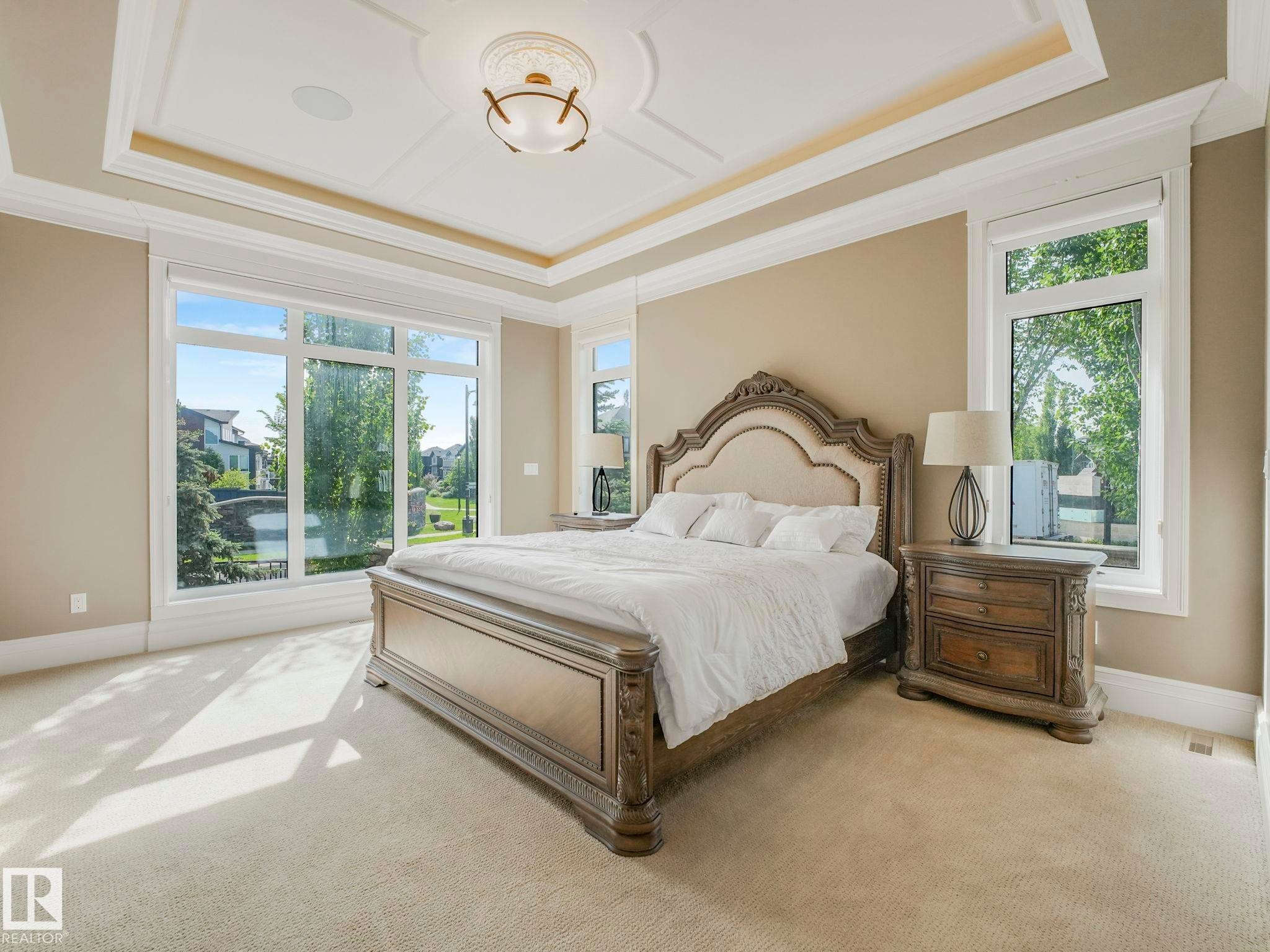 Spacious room featuring broadloom carpeting, extensive picture windows, a coffered ceiling with a central decorative light fixture, and wide crown molding - 2807 Wheaton Drive, Edmonton, AB
