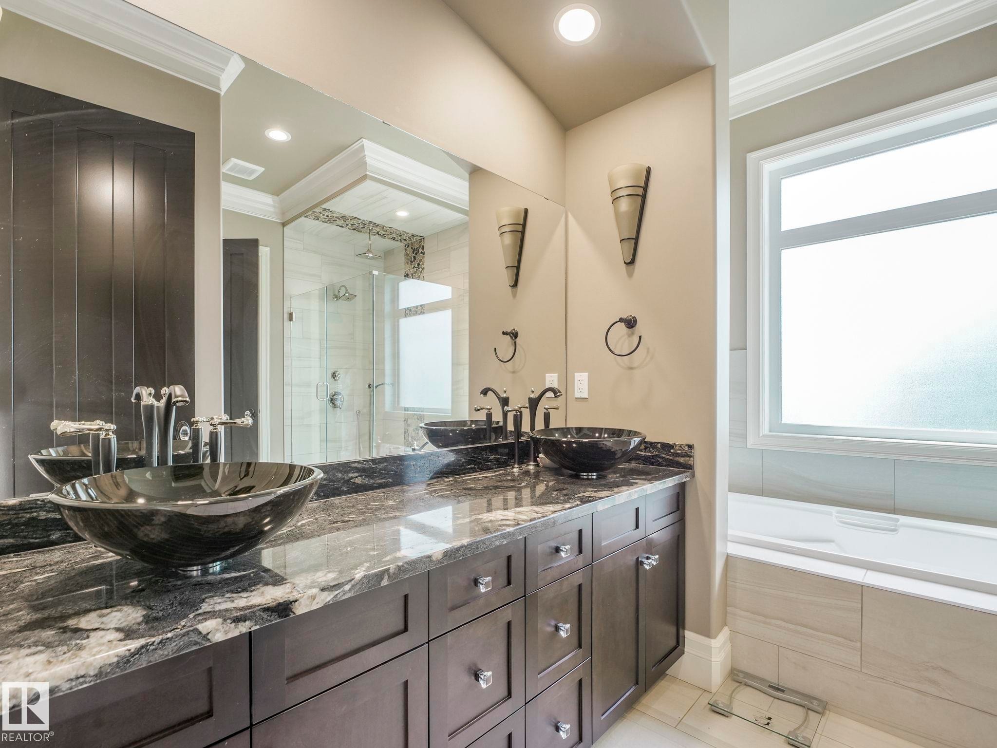 Dual vessel sinks with bronze fixtures set into a variegated stone countertop - 2807 Wheaton Drive, Edmonton, AB