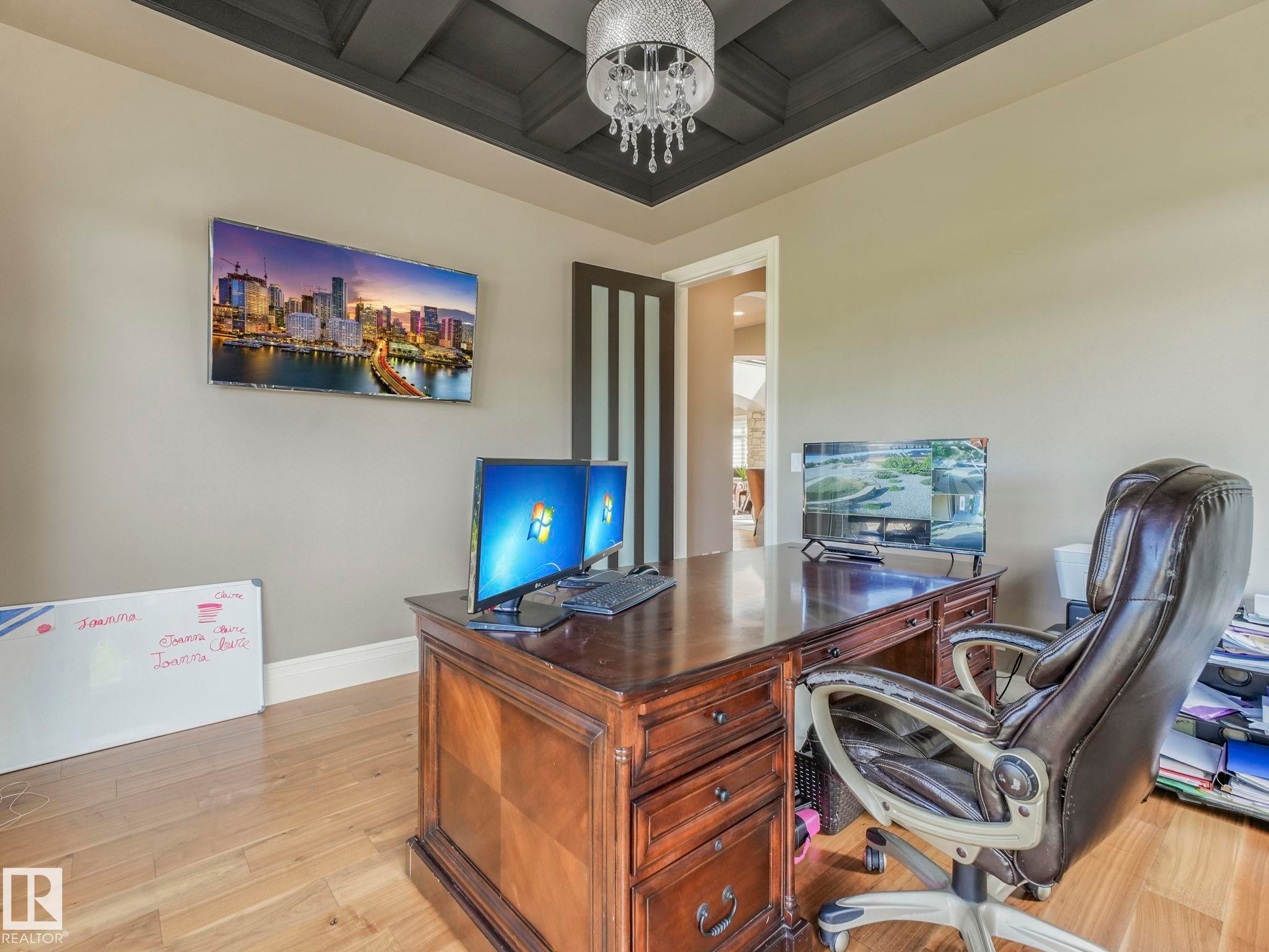 Recessed coffer ceiling with dark wood-finish accents, light wood-finish flooring, and a crystal chandelier - 2807 Wheaton Drive, Edmonton, AB
