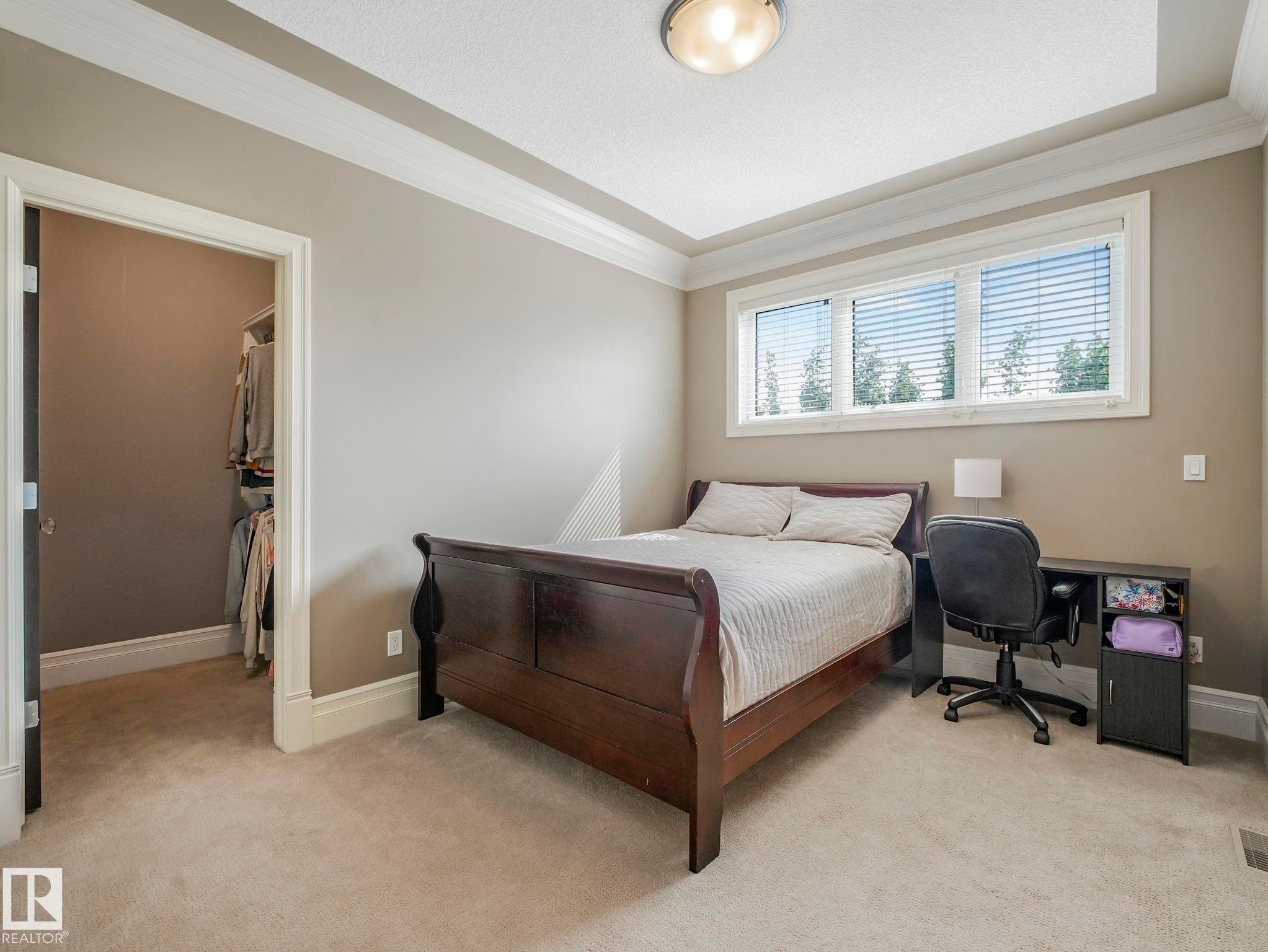 Carpeted room featuring a wide window with horizontal blinds, tray ceiling, and crown molding - 2807 Wheaton Drive, Edmonton, AB