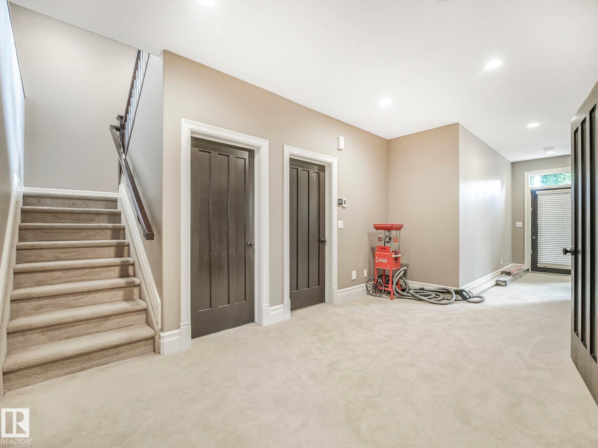 Plush carpeting extends across this versatile space, featuring paneled interior doors and a carpeted staircase with a dark wood handrail - 2807 Wheaton Drive, Edmonton, AB