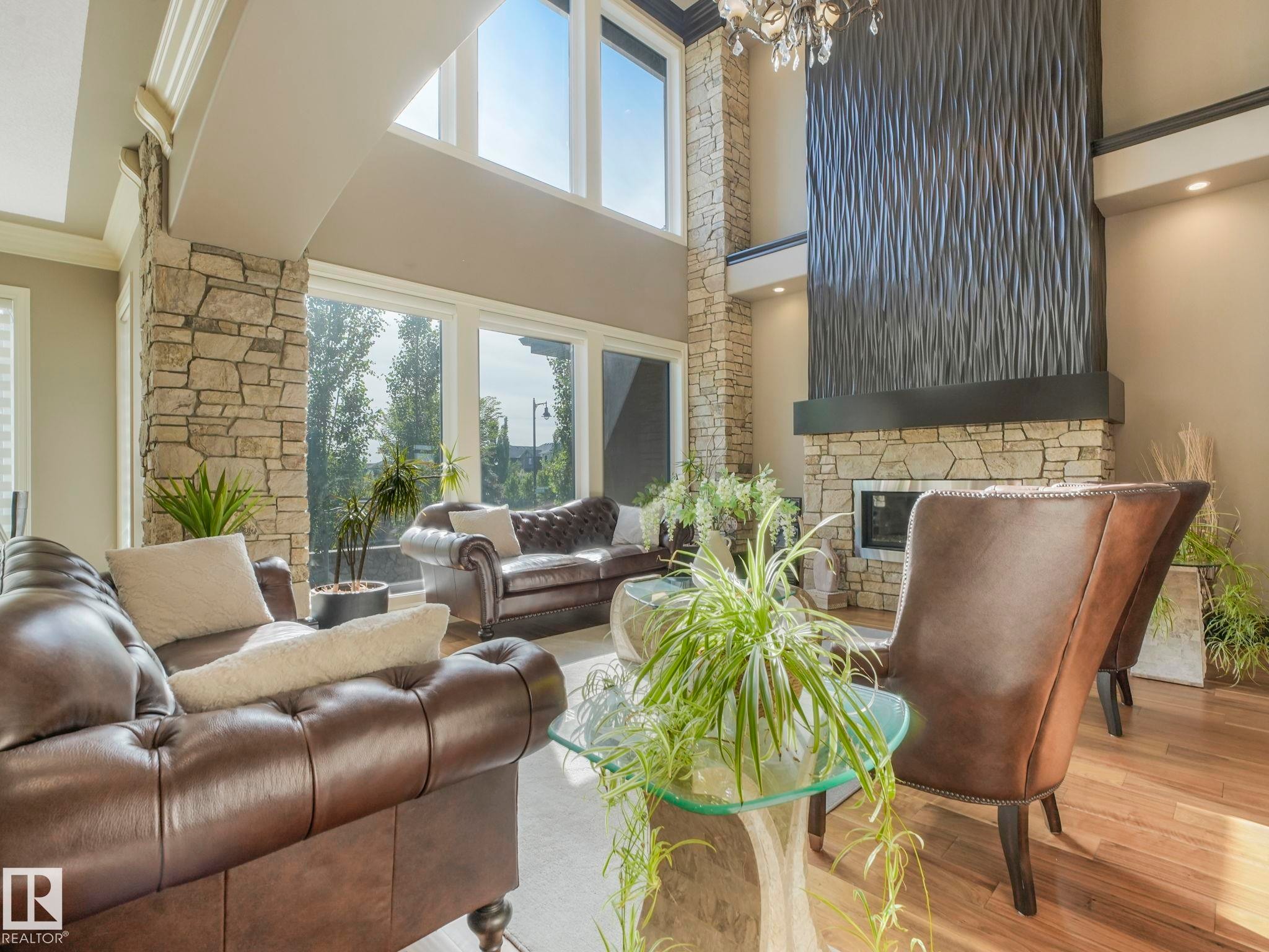 Spacious living area featuring a two-story ceiling, stone accent columns, and wood-finish flooring - 2807 Wheaton Drive, Edmonton, AB