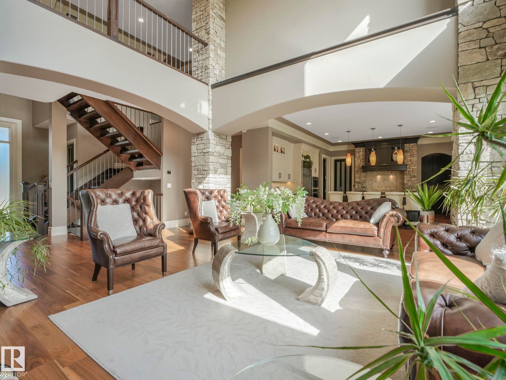 Two-story living area featuring wood-finish flooring, a stone accent wall, and an open second-story walkway with metal balusters - 2807 Wheaton Drive, Edmonton, AB