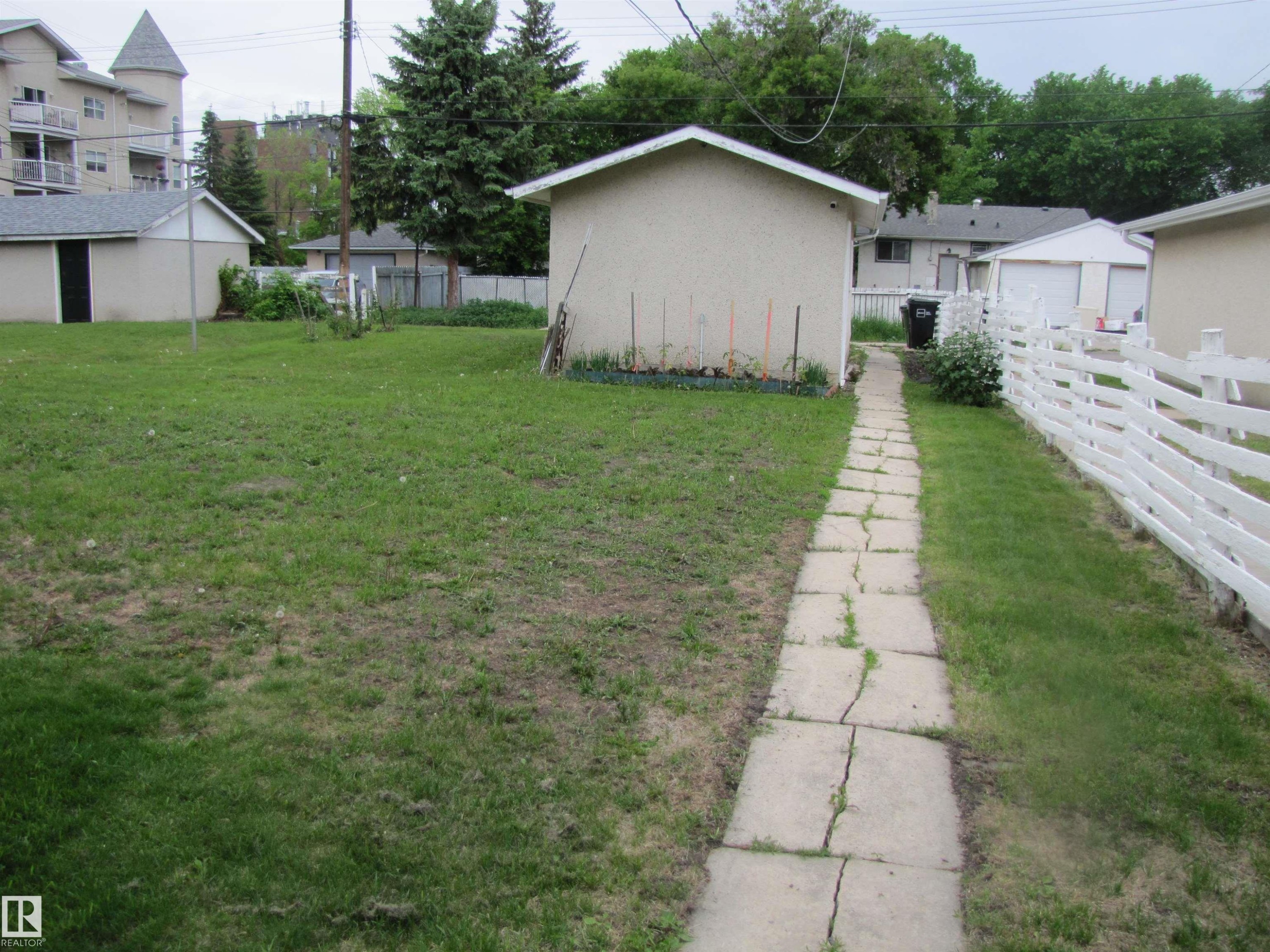 Expansive grassy yard with a white picket fence and a concrete slab pathway - 8122 83 Avenue, Edmonton, AB