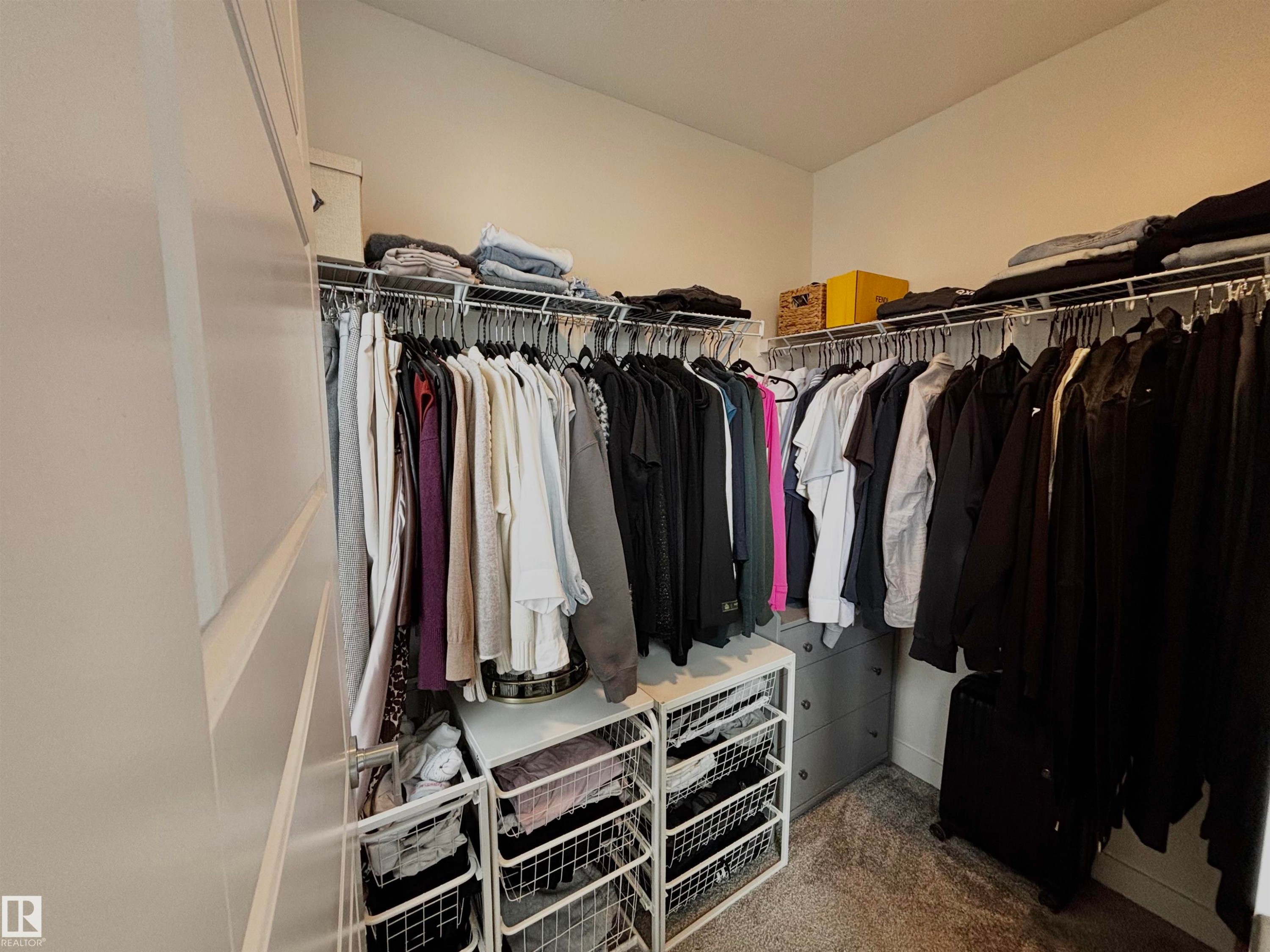 Walk-in closet featuring built-in wire shelving, multiple hanging rods, and a gray carpeted floor - 5281 Edgemont Boulevard, Edmonton, AB