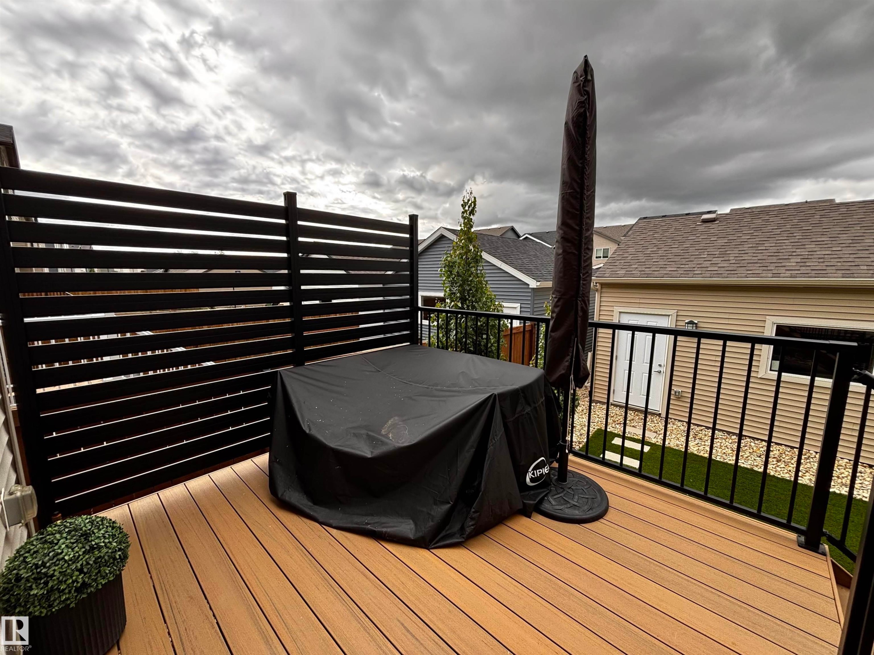 Outdoor deck featuring composite wood-finish flooring, a black horizontal slat privacy screen, and black metal railings - 5281 Edgemont Boulevard, Edmonton, AB