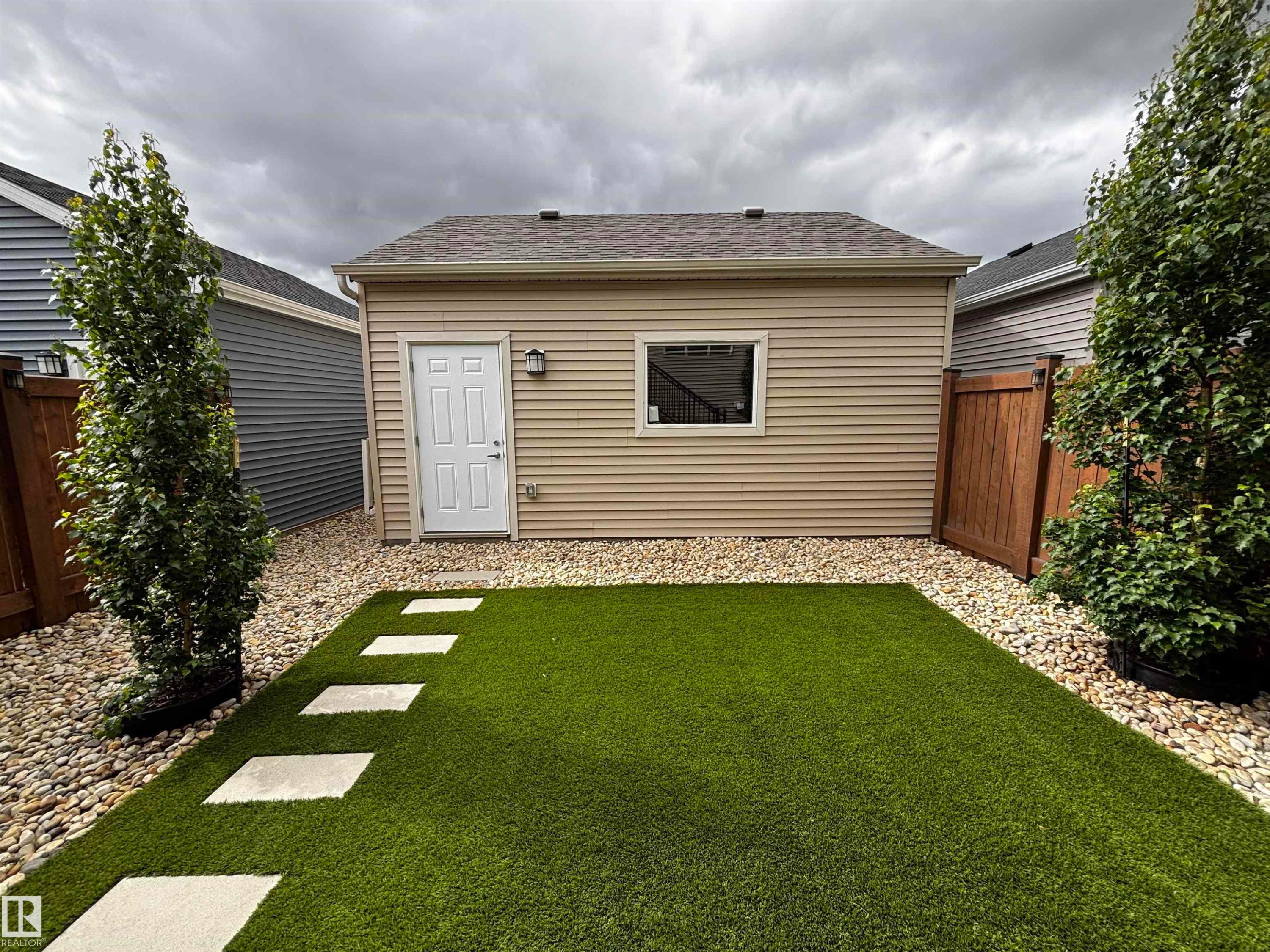 Rear detached structure featuring beige horizontal siding, a white service door, and a single window - 5281 Edgemont Boulevard, Edmonton, AB