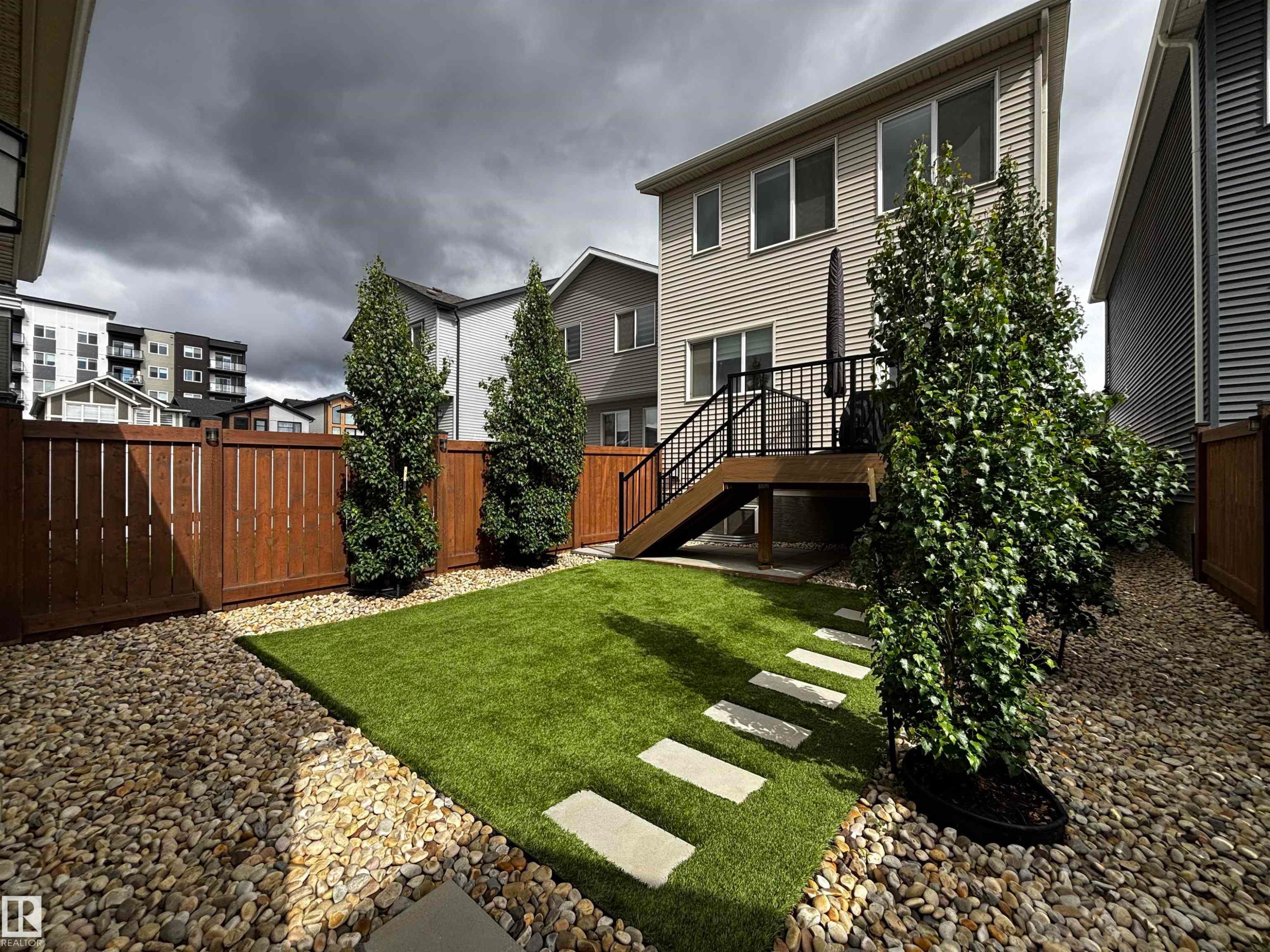 Private backyard featuring artificial turf, stepping stones, and mature trees - 5281 Edgemont Boulevard, Edmonton, AB