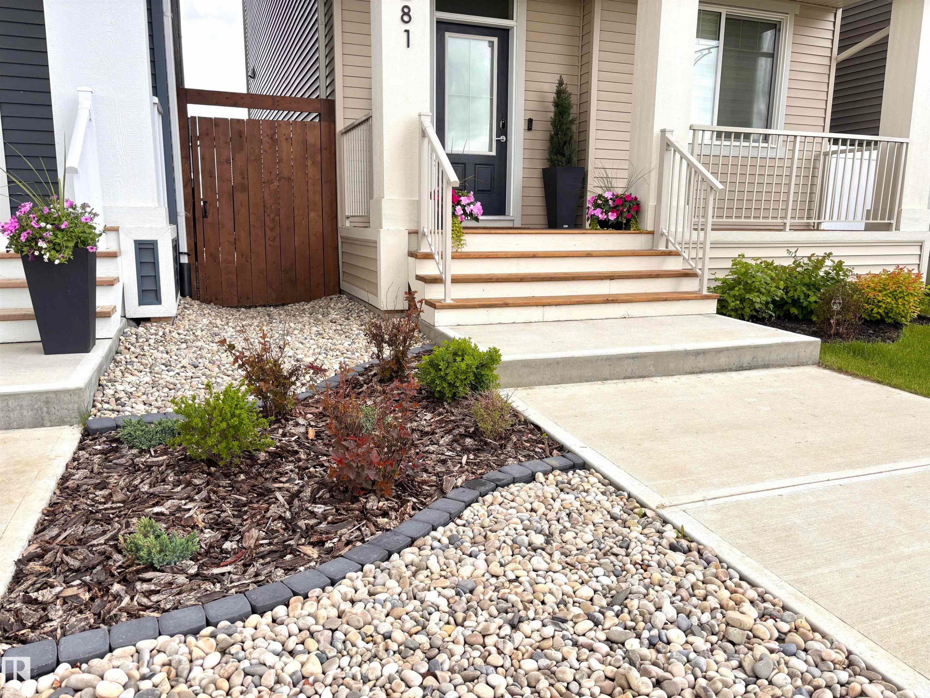 Front exterior featuring concrete steps with wood-finish risers, a wood privacy fence, and a concrete walkway - 5281 Edgemont Boulevard, Edmonton, AB