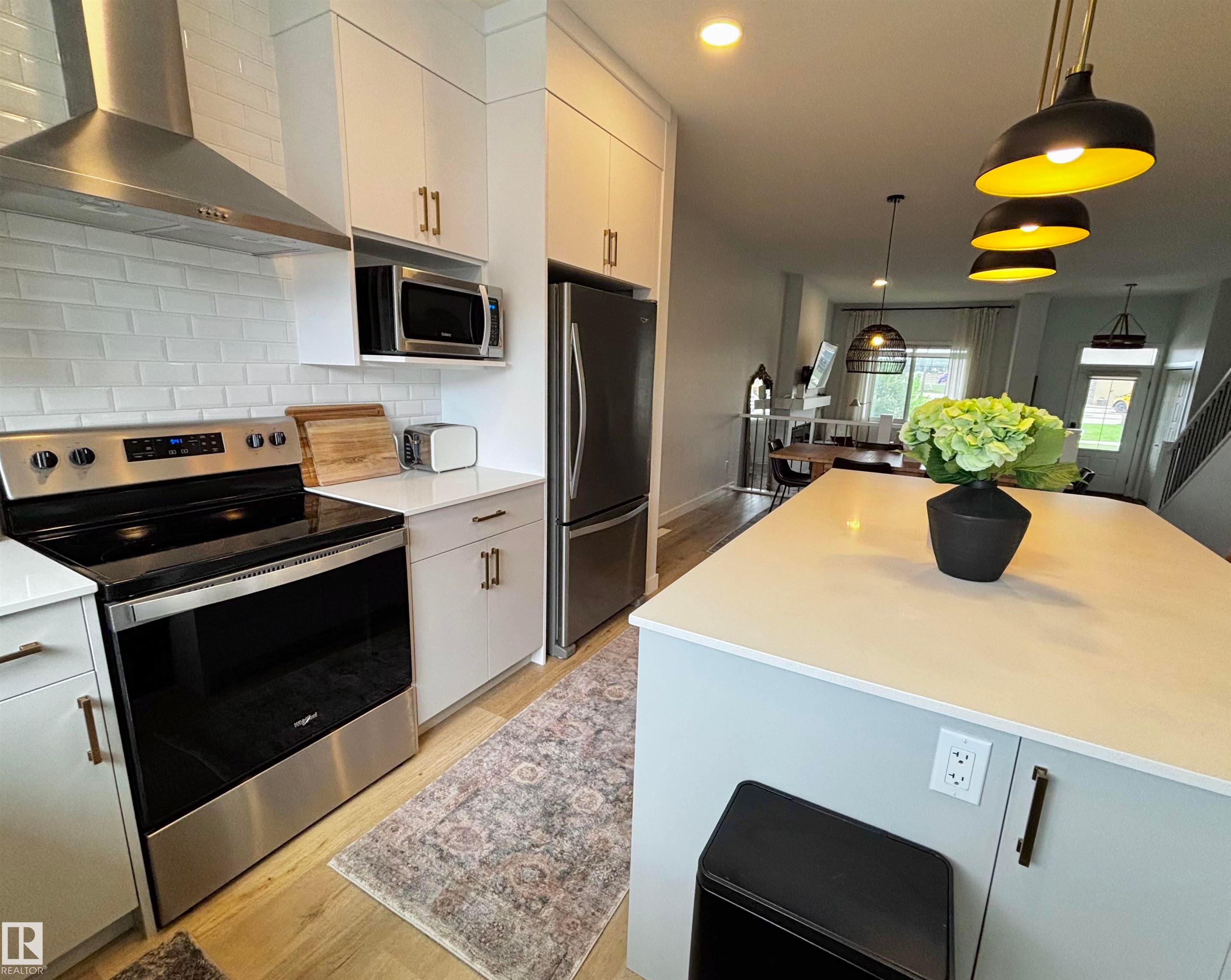 Kitchen featuring a stainless steel range, coordinating microwave, and a side-by-side refrigerator - 5281 Edgemont Boulevard, Edmonton, AB