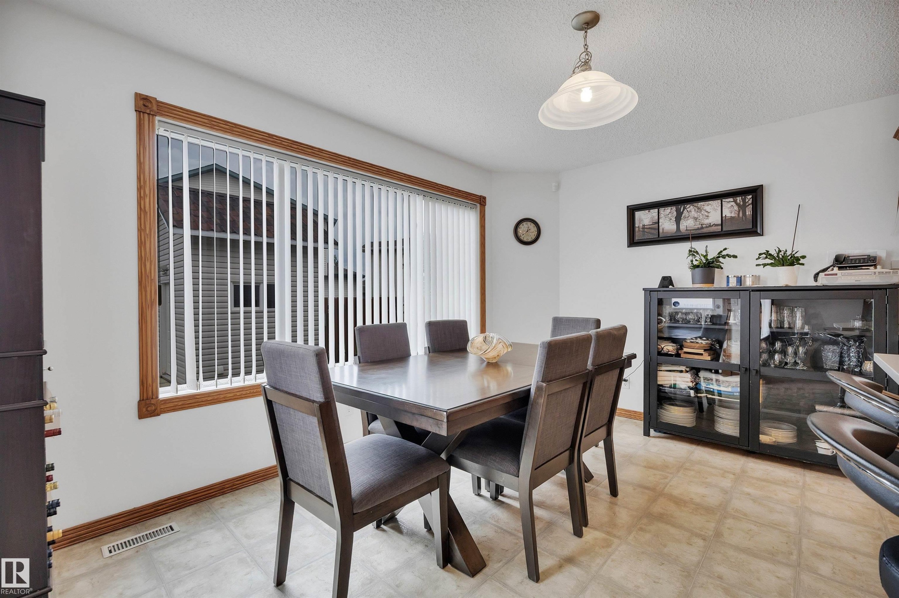 Bright dining area featuring a prominent window with vertical blinds, light-toned flooring, and a ceiling-mounted light fixture - 16512 87 Street Nw, Edmonton, AB - Indoor Photo Showing Dining Room