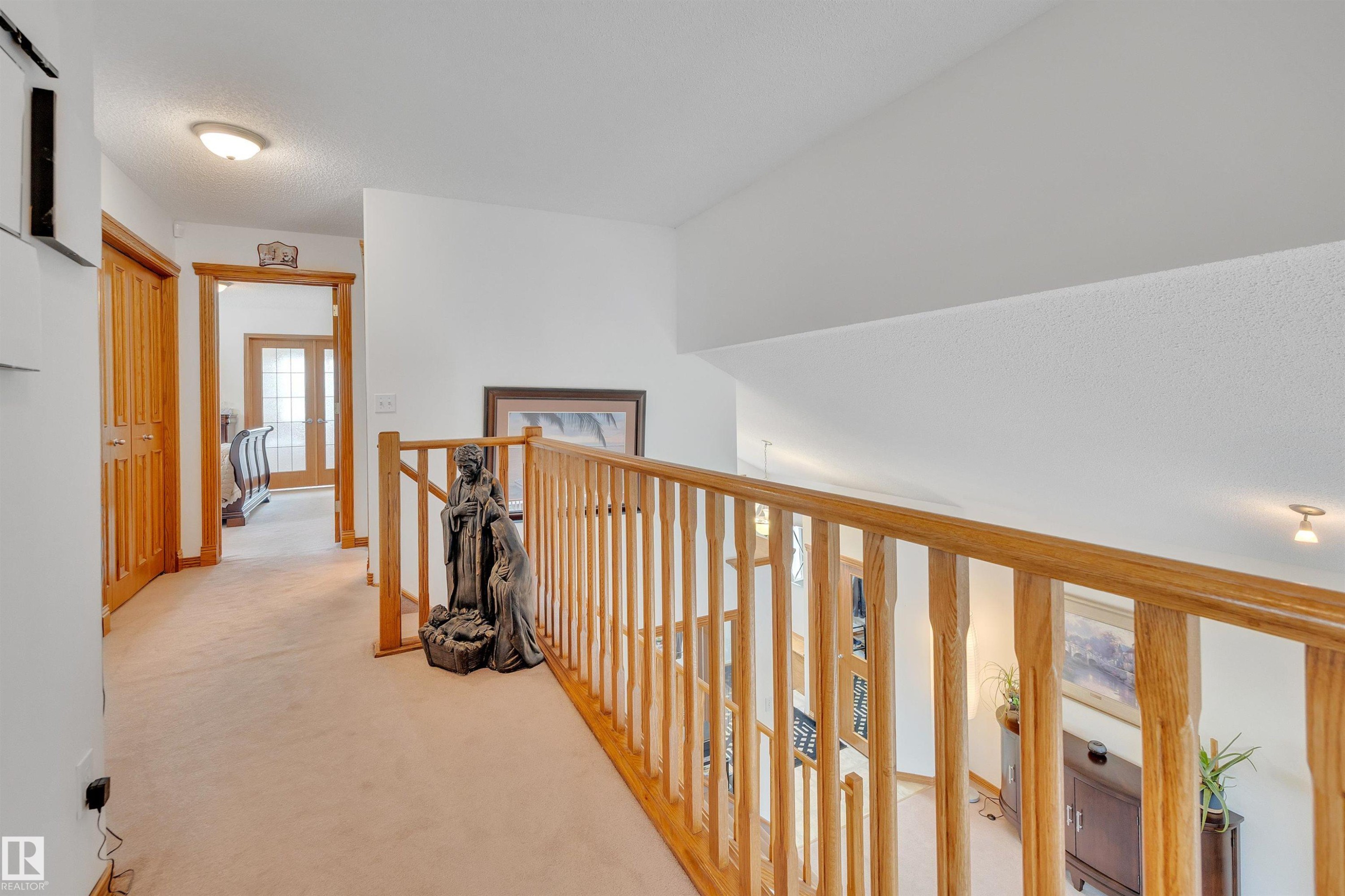 Upper-level hallway with light-colored carpeting, white walls, and a natural wood railing overlooking the lower level - 16512 87 Street Nw, Edmonton, AB - Indoor Photo Showing Other Room