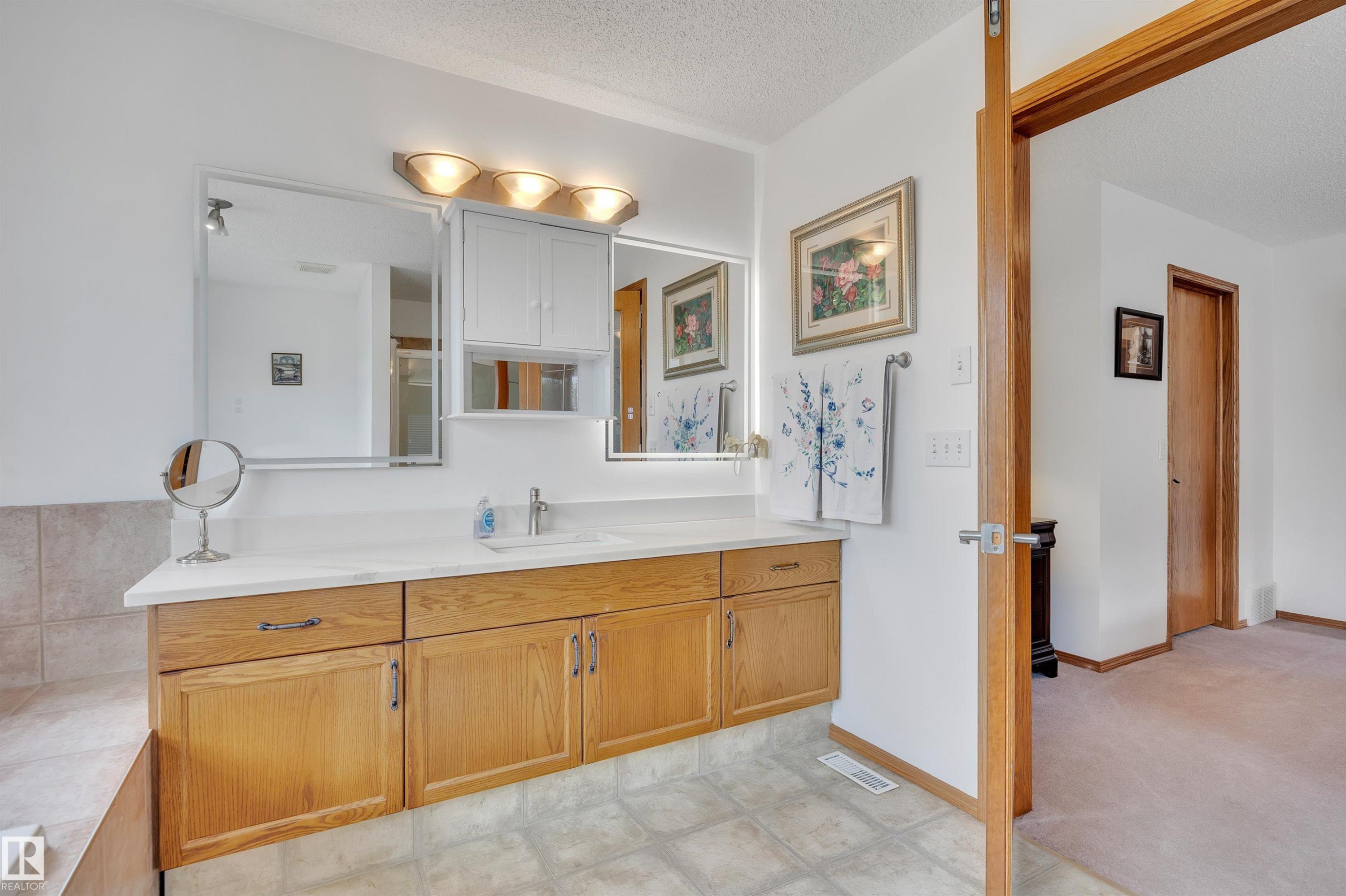 Double vanity with a single basin, light wood-finish cabinetry, and a light-colored countertop - 16512 87 Street Nw, Edmonton, AB - Indoor