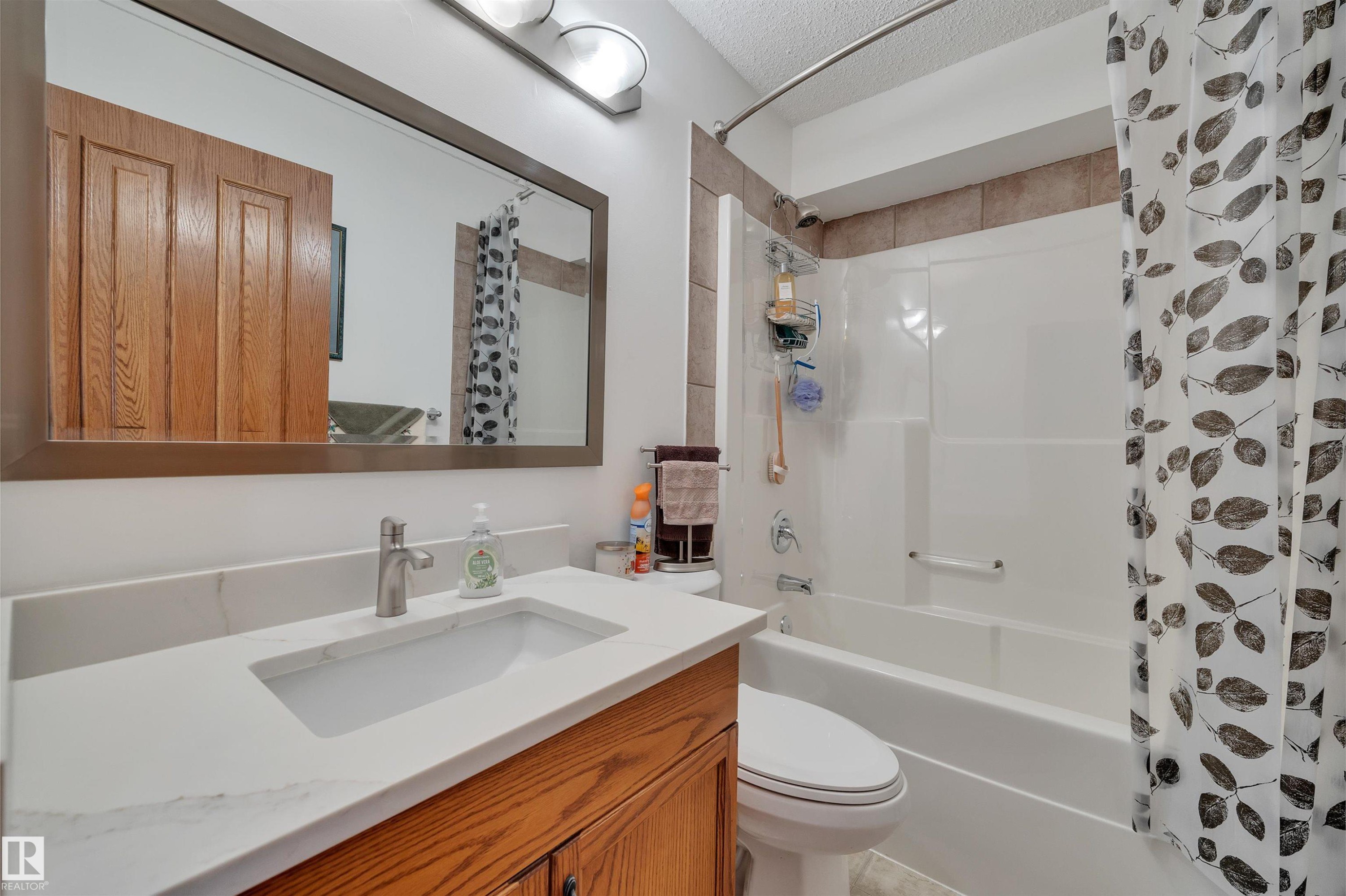 Bathroom vanity with a rectangular undermount sink, a brushed nickel faucet, and a light-toned countertop - 16512 87 Street Nw, Edmonton, AB - Indoor Photo Showing Bathroom