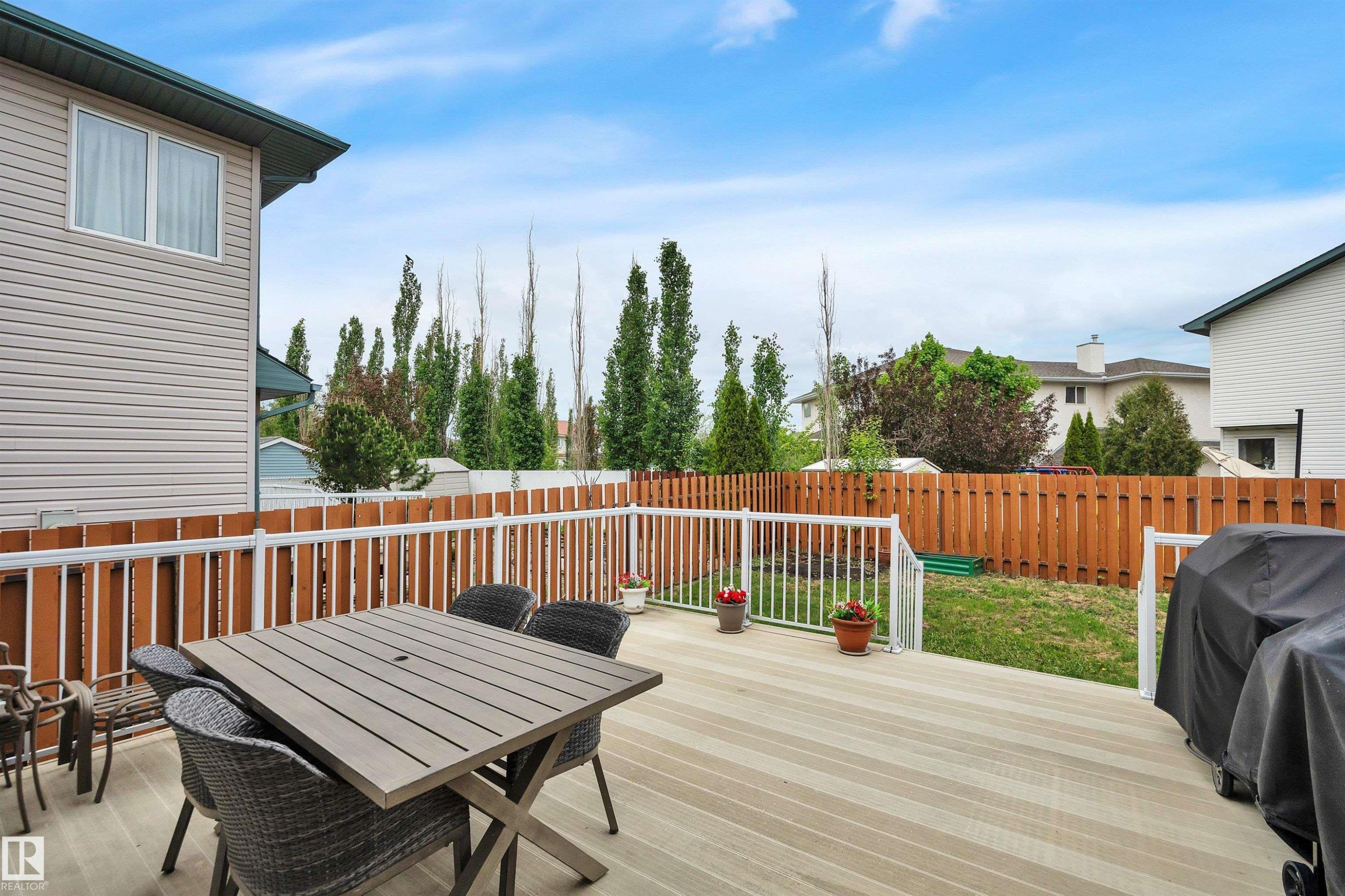 Spacious composite deck featuring white railings, a brown privacy fence, and an expansive lawn area - 16512 87 Street Nw, Edmonton, AB - Outdoor With Deck Patio Veranda With Exterior