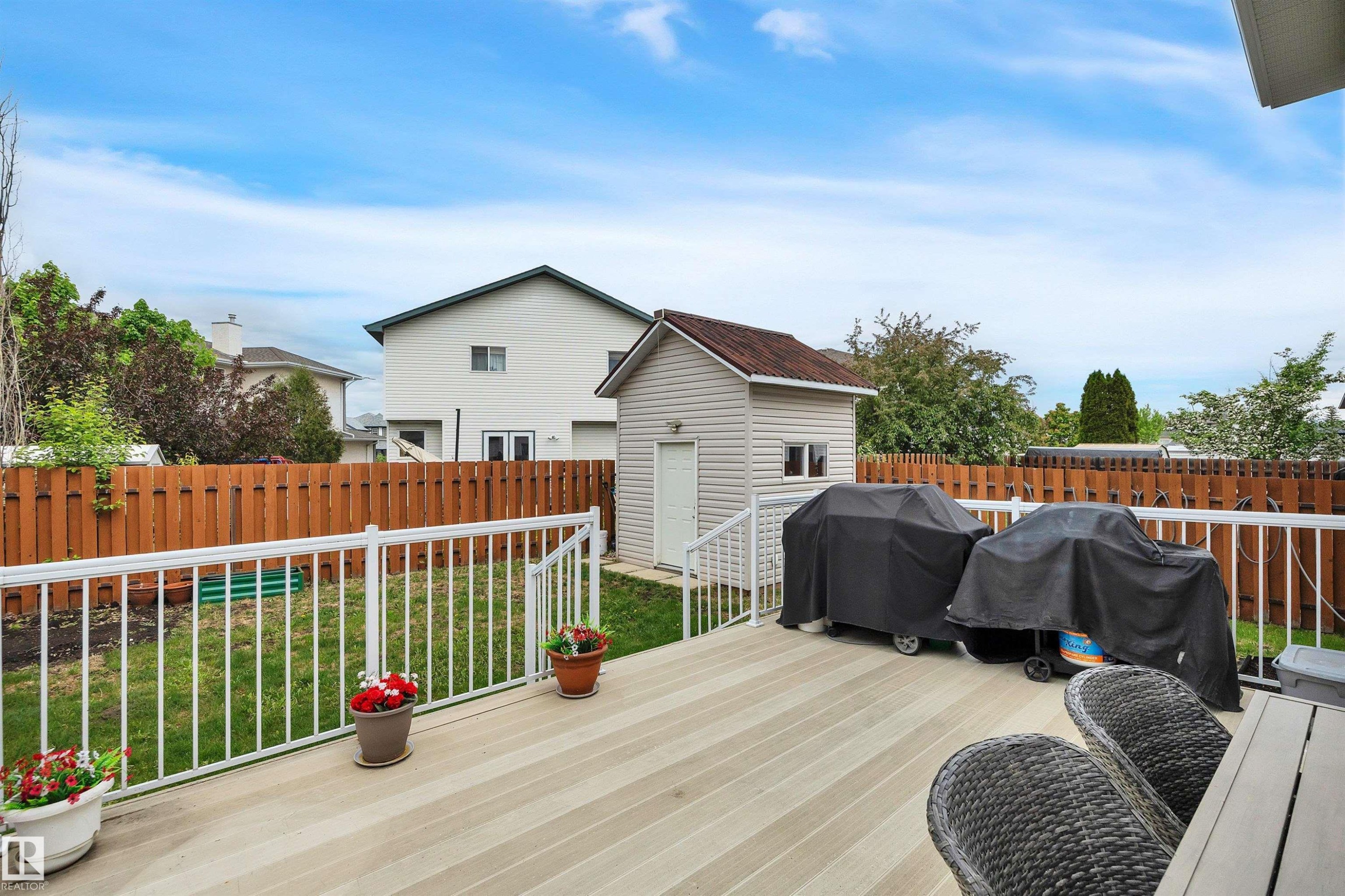 Spacious composite deck with white railings overlooks a fenced backyard featuring a detached storage shed - 16512 87 Street Nw, Edmonton, AB - Outdoor With Deck Patio Veranda With Exterior