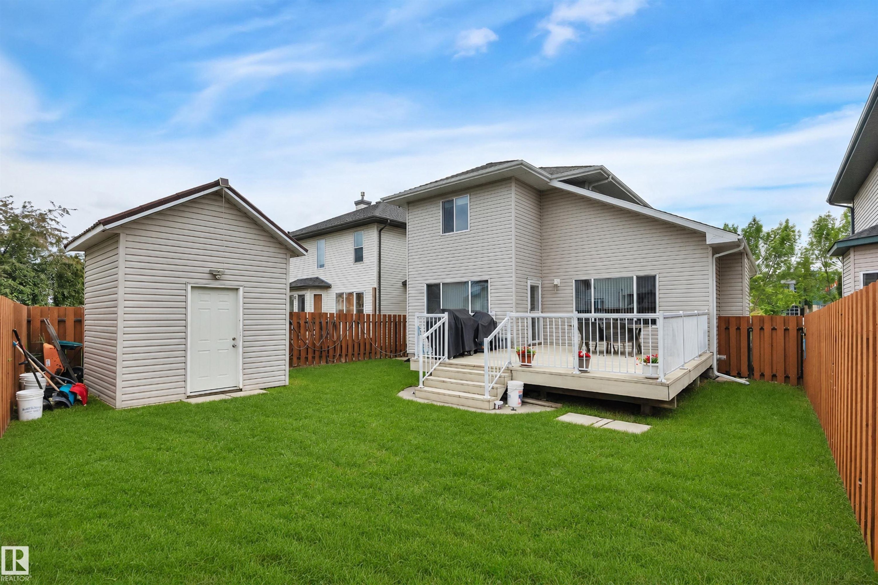 Expansive backyard, a large elevated deck with white railings, and a detached storage shed *Lawn has been Virtually enhanced* - 16512 87 Street Nw, Edmonton, AB - Outdoor With Deck Patio Veranda With Exterior