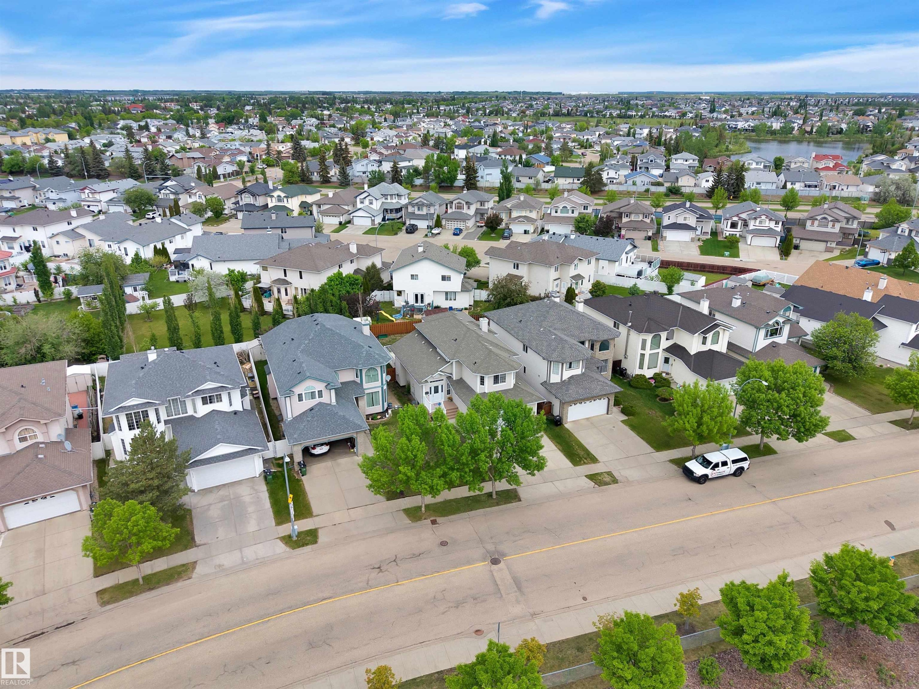 Residential street featuring mature trees, concrete sidewalks, and a variety of detached homes with attached garages - 16512 87 Street Nw, Edmonton, AB - Outdoor With View
