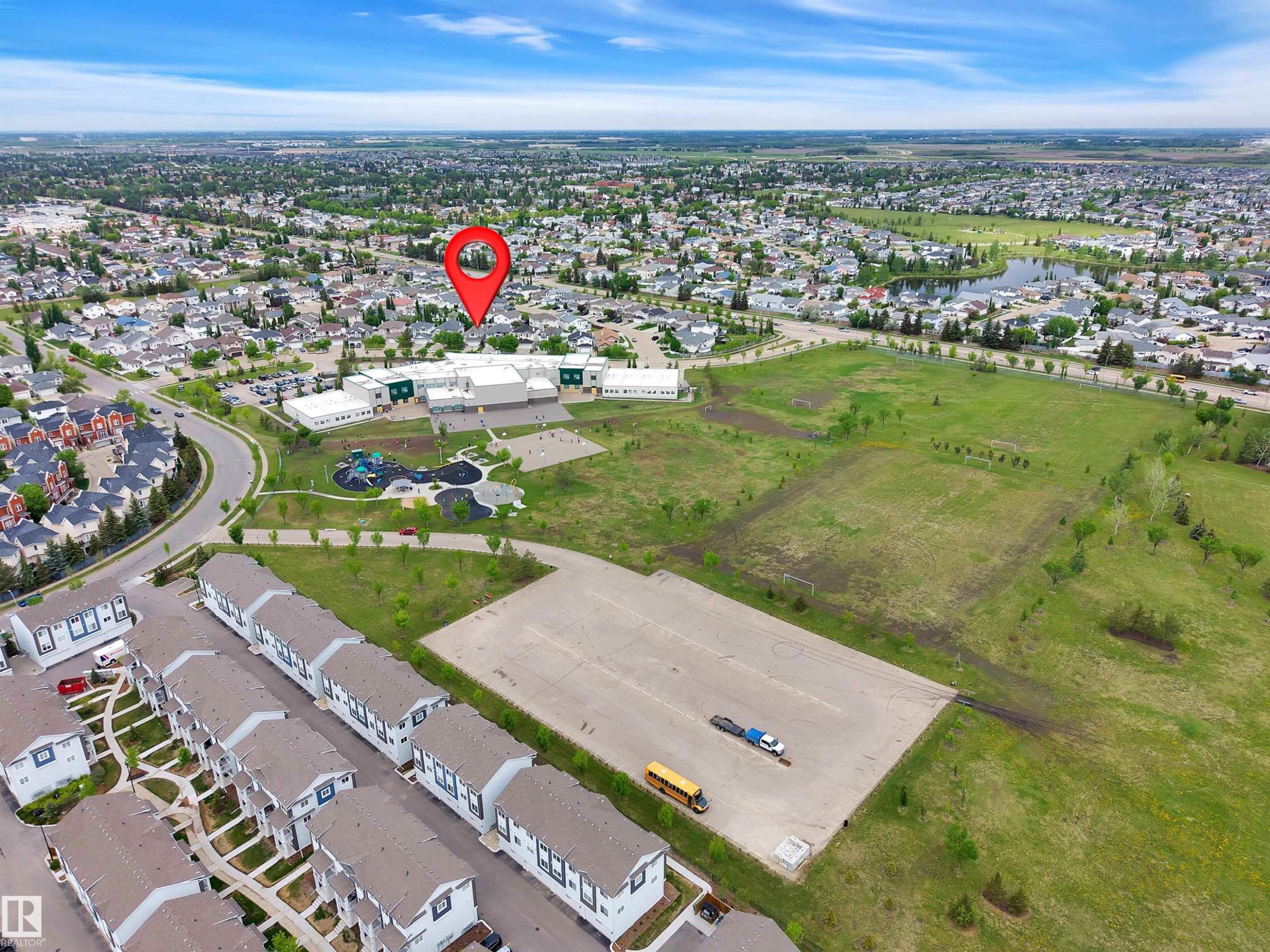 Aerial perspective of an established residential neighborhood featuring multiple housing styles, a large community building with an adjacent playground, and expansive green spaces - 16512 87 Street Nw, Edmonton, AB - Outdoor With View