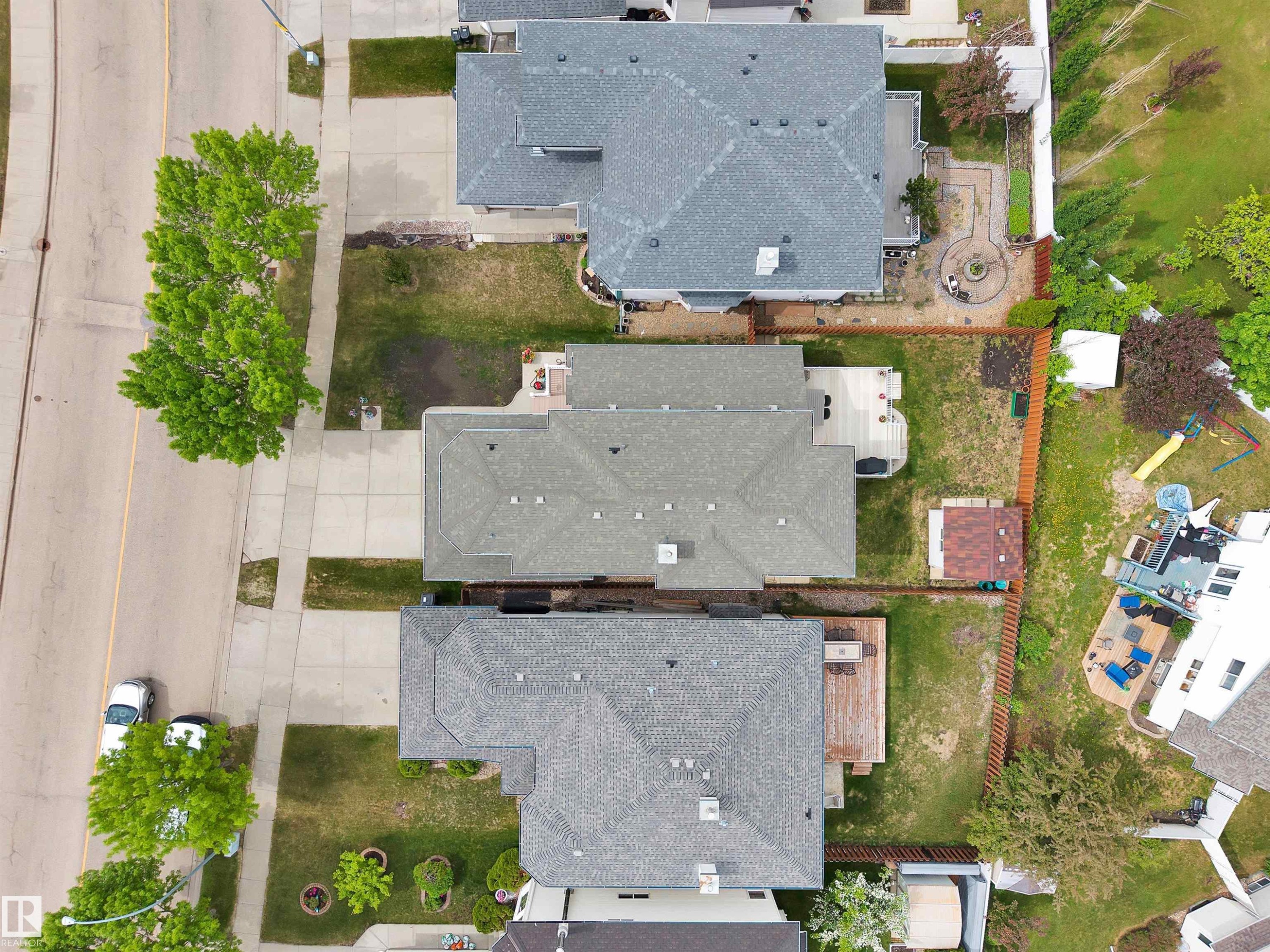 Overhead view of a residential property featuring a gray shingle roof, a rear deck, a fenced backyard, and a detached shed with a red shingle roof - 16512 87 Street Nw, Edmonton, AB - Outdoor With View