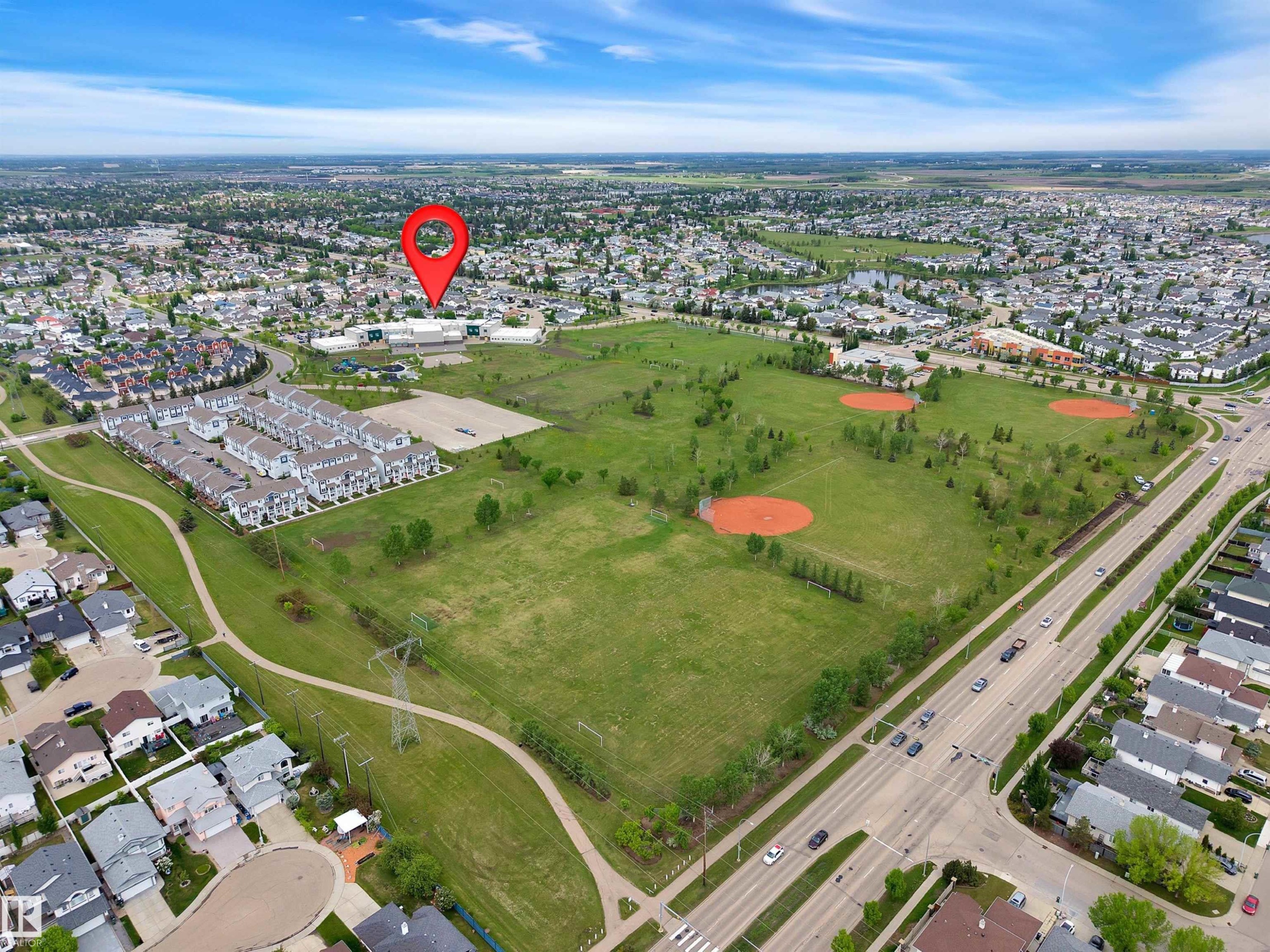 Aerial perspective showcasing a residential neighborhood with extensive green spaces, a multi-lane roadway, and light commercial buildings - 16512 87 Street Nw, Edmonton, AB - Outdoor With View