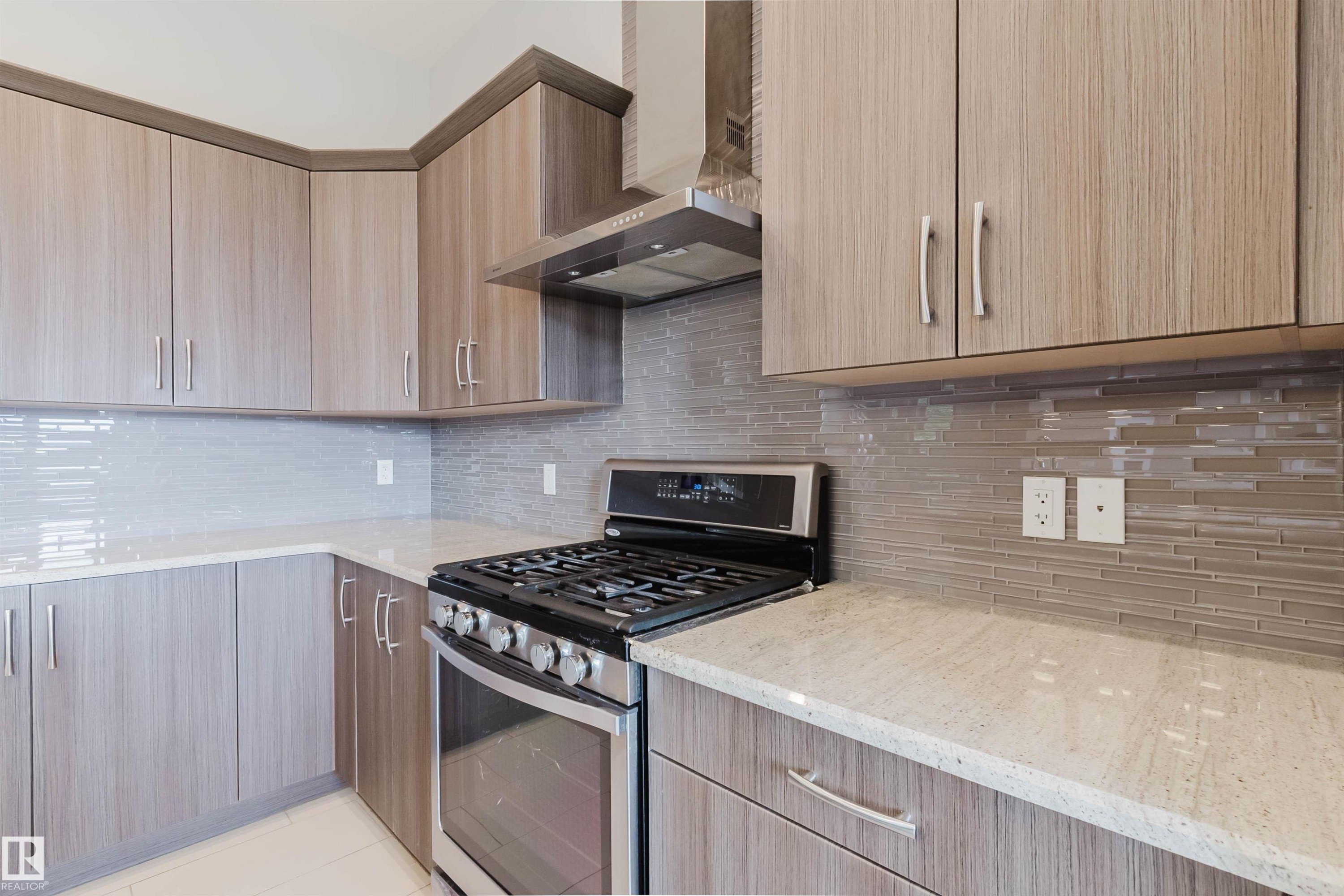 Modern kitchen featuring extensive wood-finish cabinetry, light-toned countertops, a full stainless steel range, and a sleek tile backsplash - 2921 Anderson Crest Sw, Edmonton, AB - Indoor Photo Showing Kitchen With Upgraded Kitchen