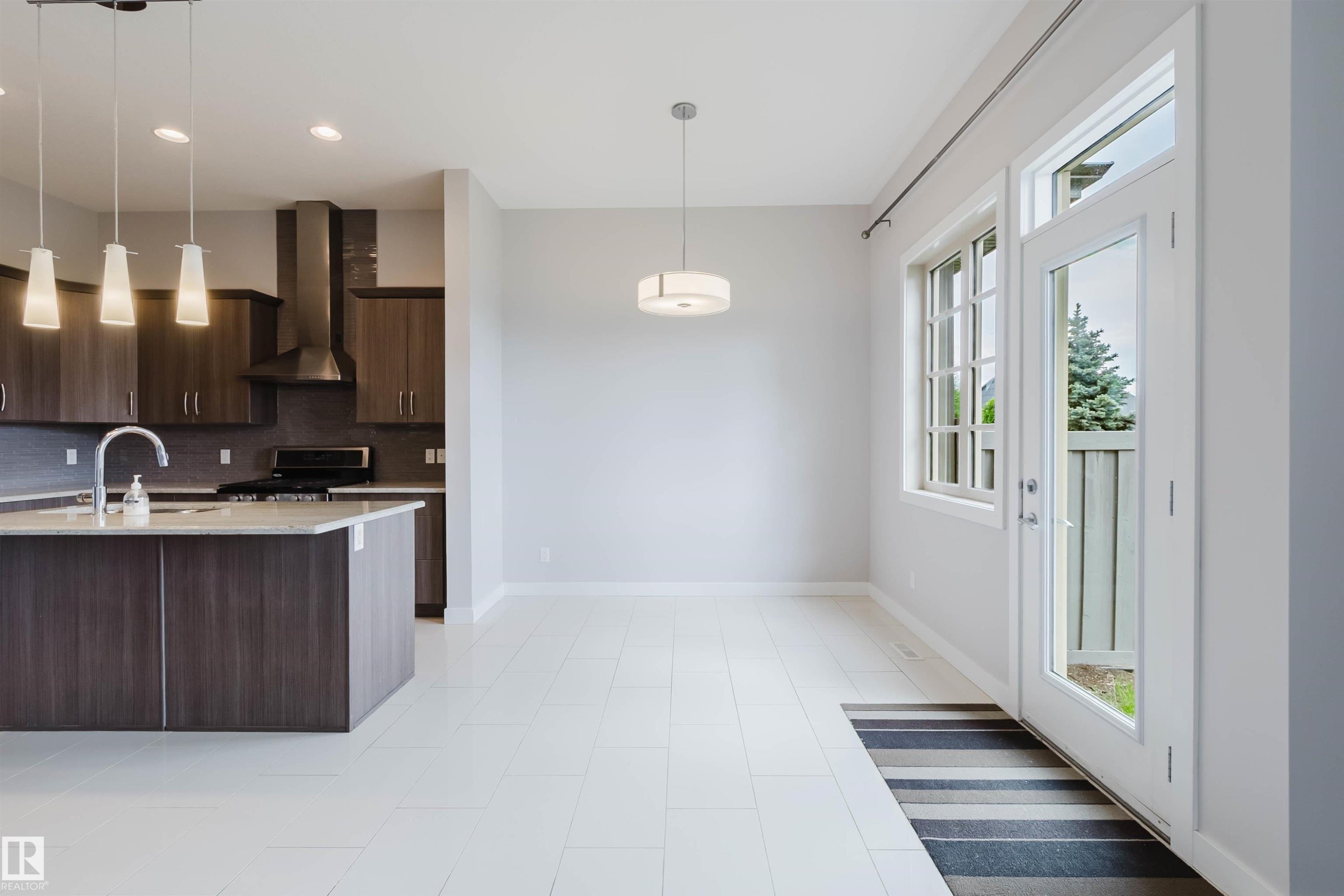 Open-concept living space featuring a kitchen island with pendant lighting, stone countertops, and dark wood-finish cabinetry - 2921 Anderson Crest Sw, Edmonton, AB - Indoor Photo Showing Other Room