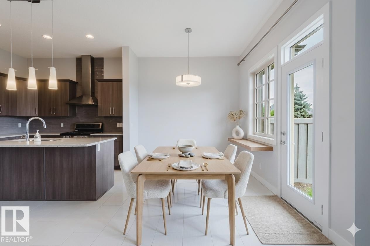 Bright dining area featuring a light wood-finish table, white tile flooring, and a contemporary pendant light fixture - 2921 Anderson Crest Sw, Edmonton, AB - Indoor Photo Showing Dining Room