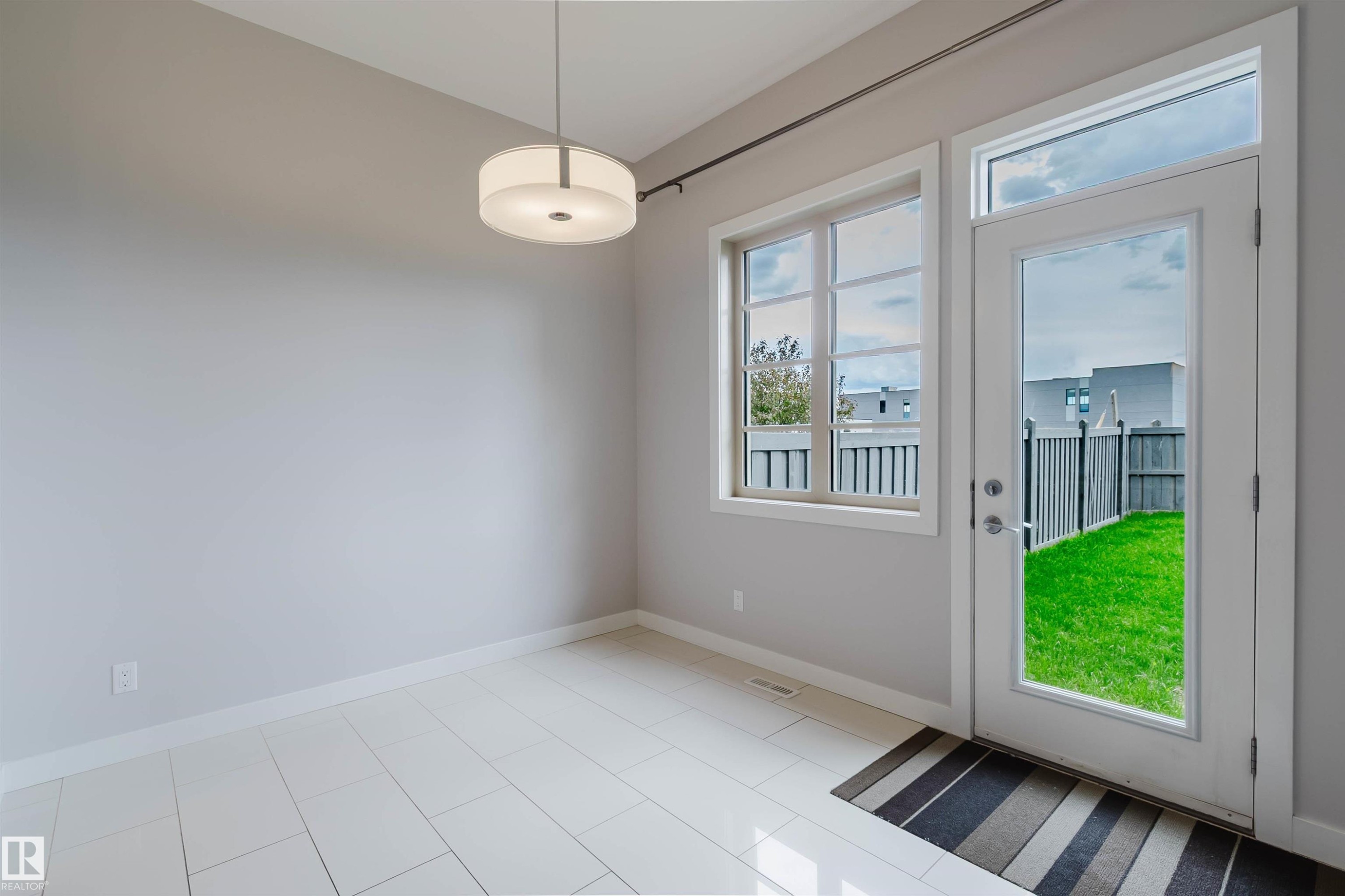 Contemporary interior space featuring light gray walls, large format tile flooring, and a modern drum pendant light fixture - 2921 Anderson Crest Sw, Edmonton, AB - Indoor Photo Showing Other Room