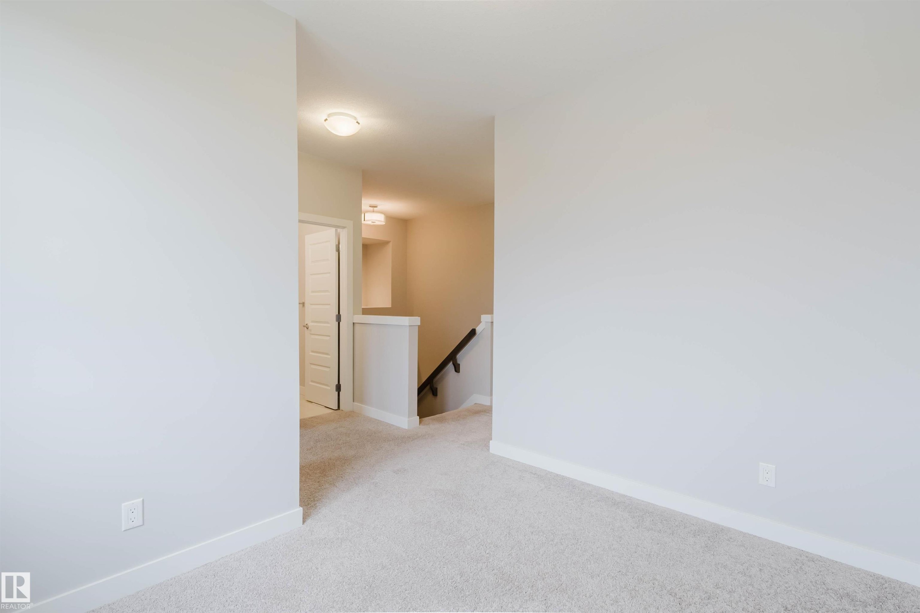 Carpeted room with light-toned walls, white baseboards, and a doorway featuring a paneled door - 2921 Anderson Crest Sw, Edmonton, AB - Indoor Photo Showing Other Room