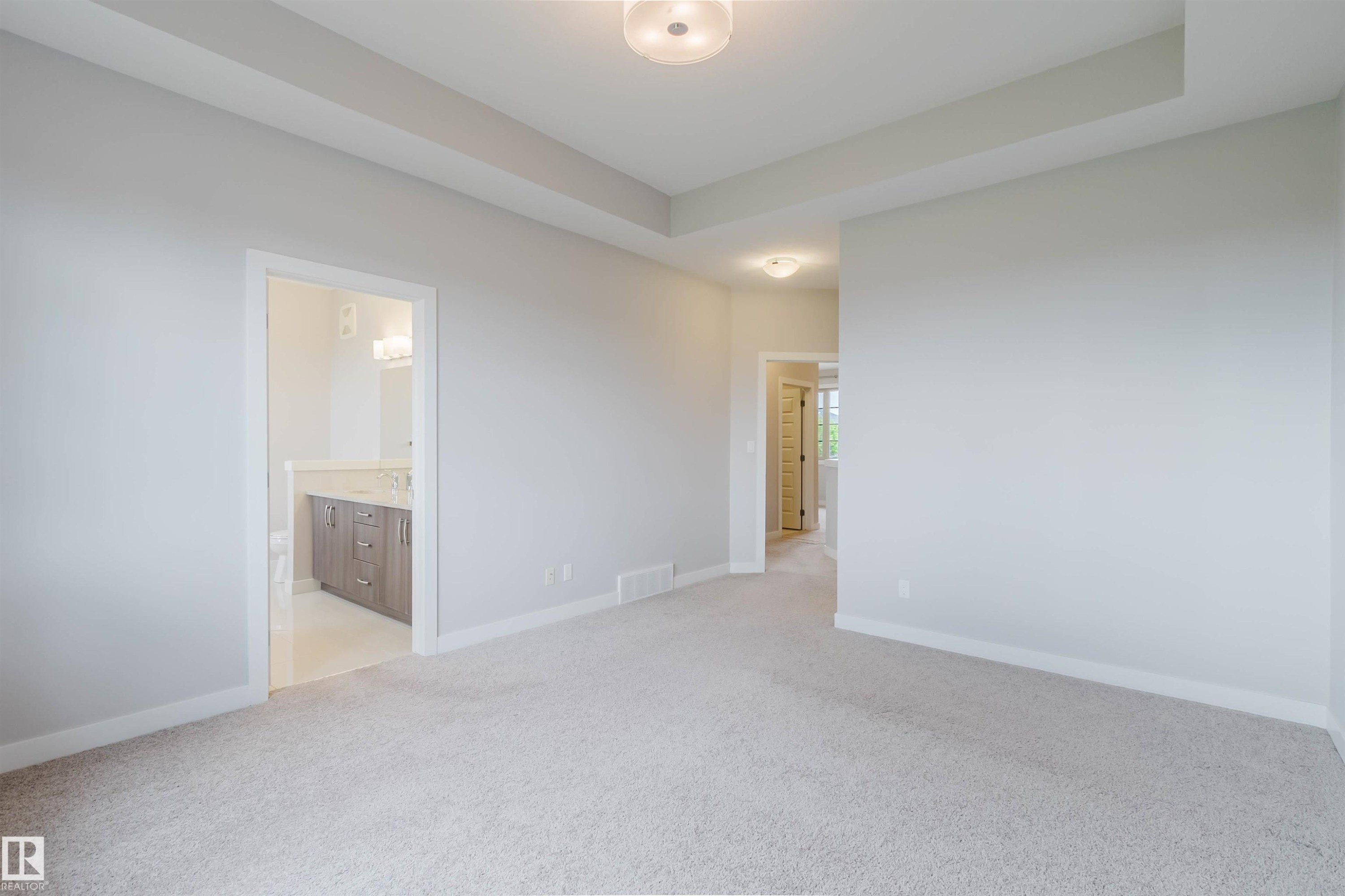 Neutral-toned carpeting extends throughout this interior space, featuring a tray ceiling with a flush-mount light fixture - 2921 Anderson Crest Sw, Edmonton, AB - Indoor Photo Showing Other Room