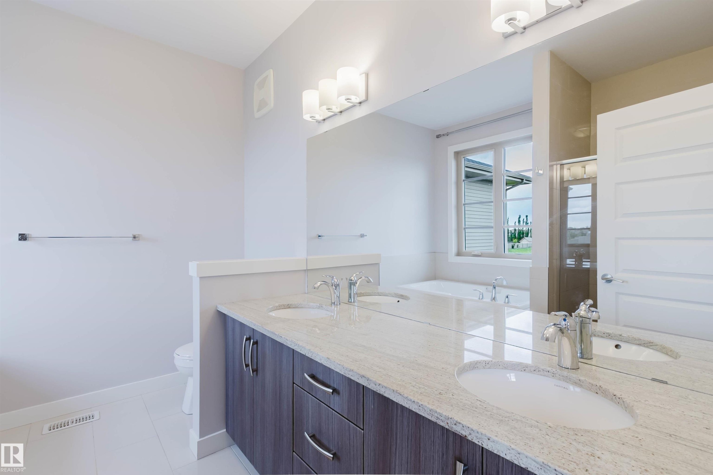 Dual vanity featuring a light-toned countertop, under-mount sinks, and chrome faucets - 2921 Anderson Crest Sw, Edmonton, AB - Indoor Photo Showing Bathroom
