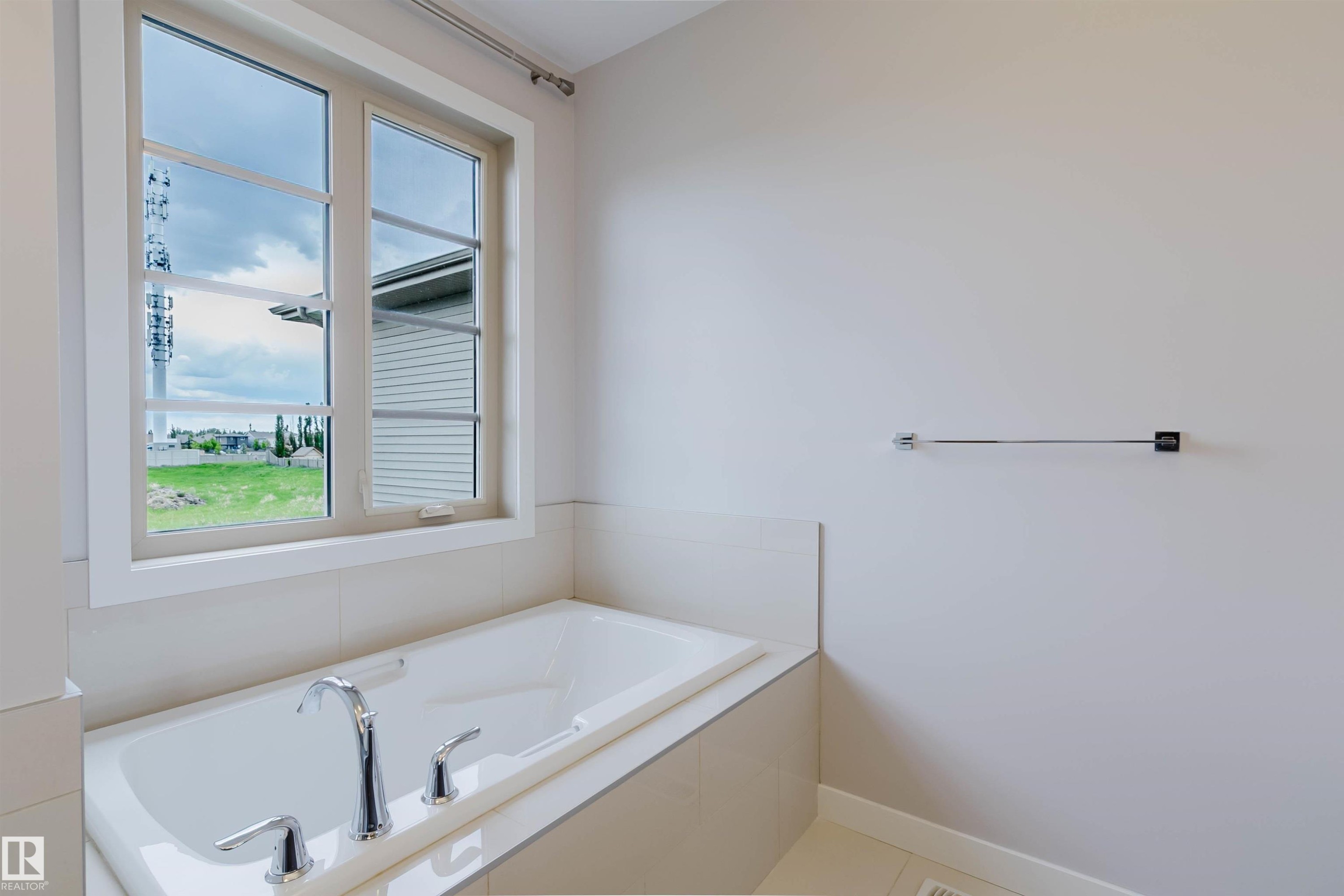 Built-in soaking tub with chrome fixtures, surrounded by neutral-toned wall tiling and a large framed window - 2921 Anderson Crest Sw, Edmonton, AB - Indoor Photo Showing Bathroom