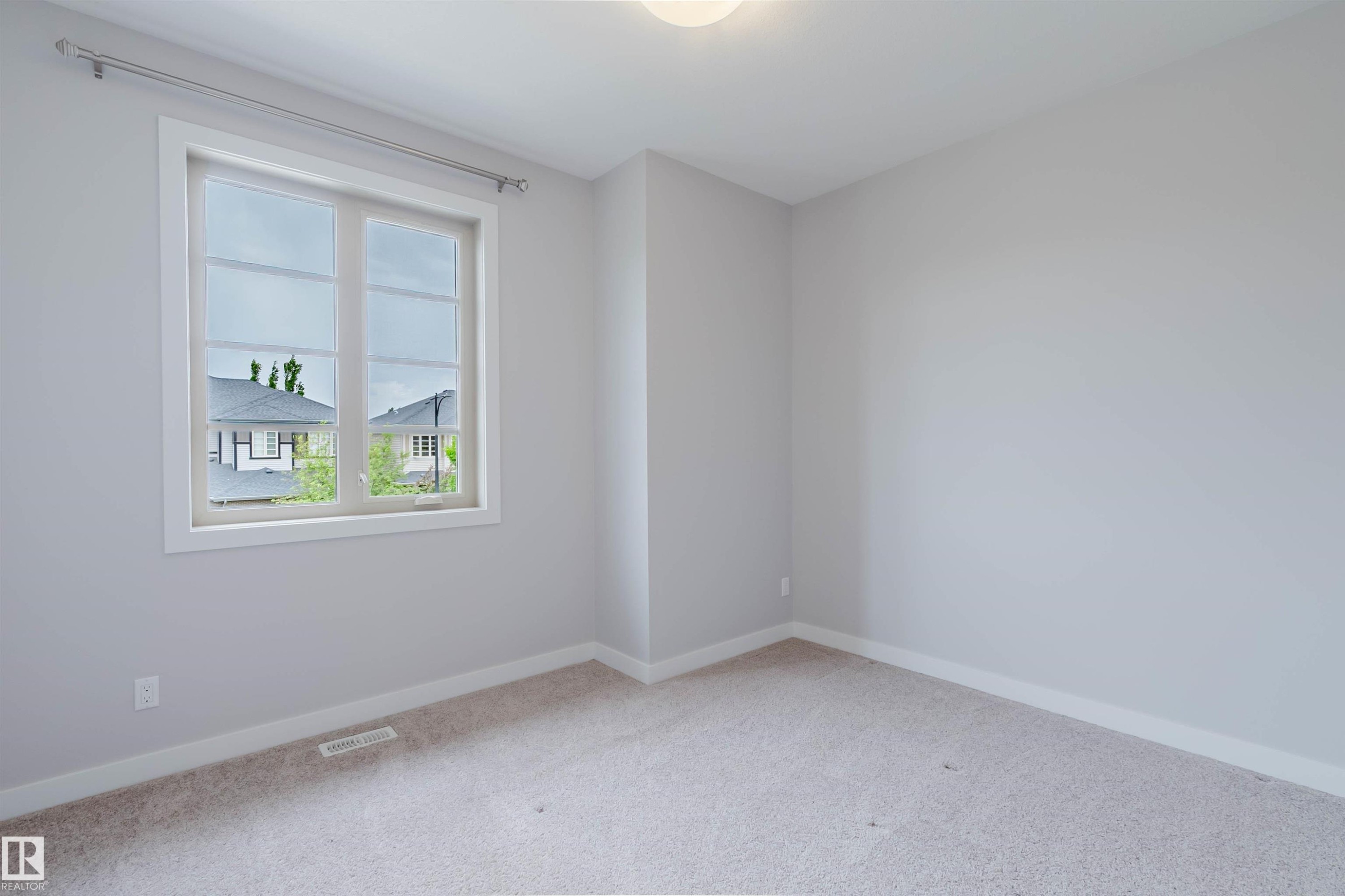 Bright interior room featuring a large window with white trim, neutral wall tones, light-colored carpeting, and a flush-mount ceiling light fixture - 2921 Anderson Crest Sw, Edmonton, AB - Indoor Photo Showing Other Room