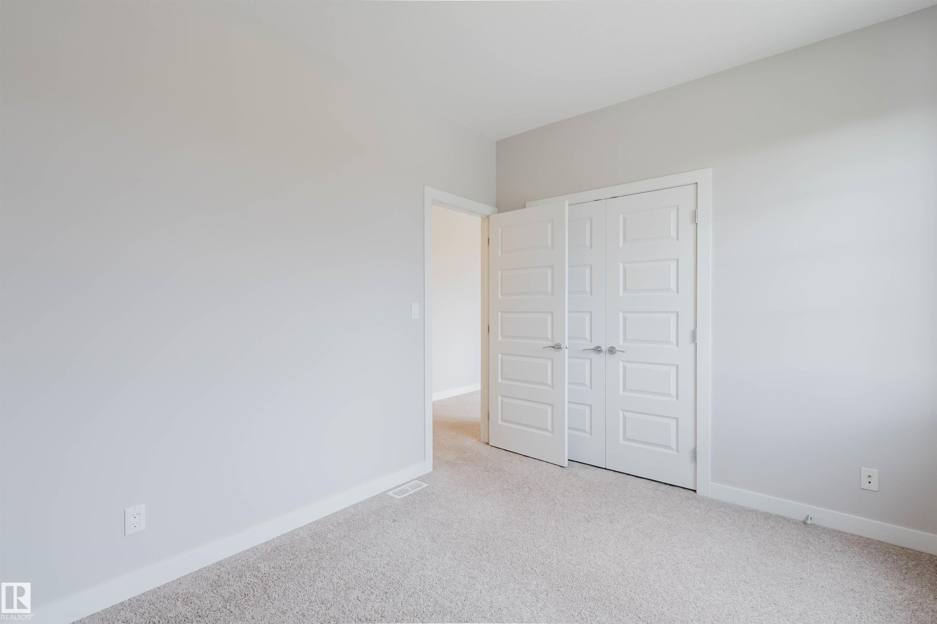 Neutral tone walls with white trim, light-colored carpet, and paneled double doors - 2921 Anderson Crest Sw, Edmonton, AB - Indoor Photo Showing Other Room
