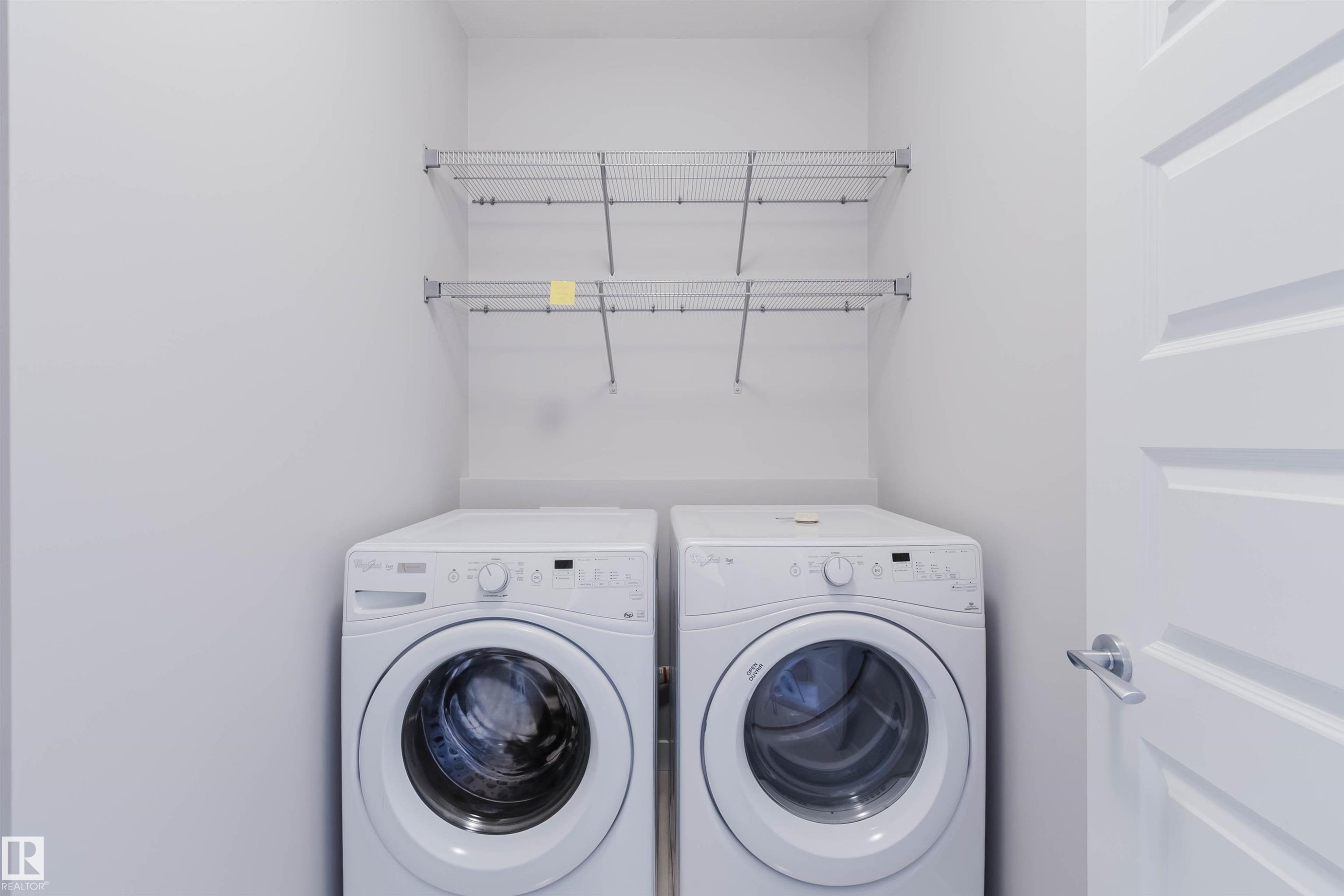 Dedicated laundry area featuring front-loading appliances, white walls, and built-in wire shelving - 2921 Anderson Crest Sw, Edmonton, AB - Indoor Photo Showing Laundry Room