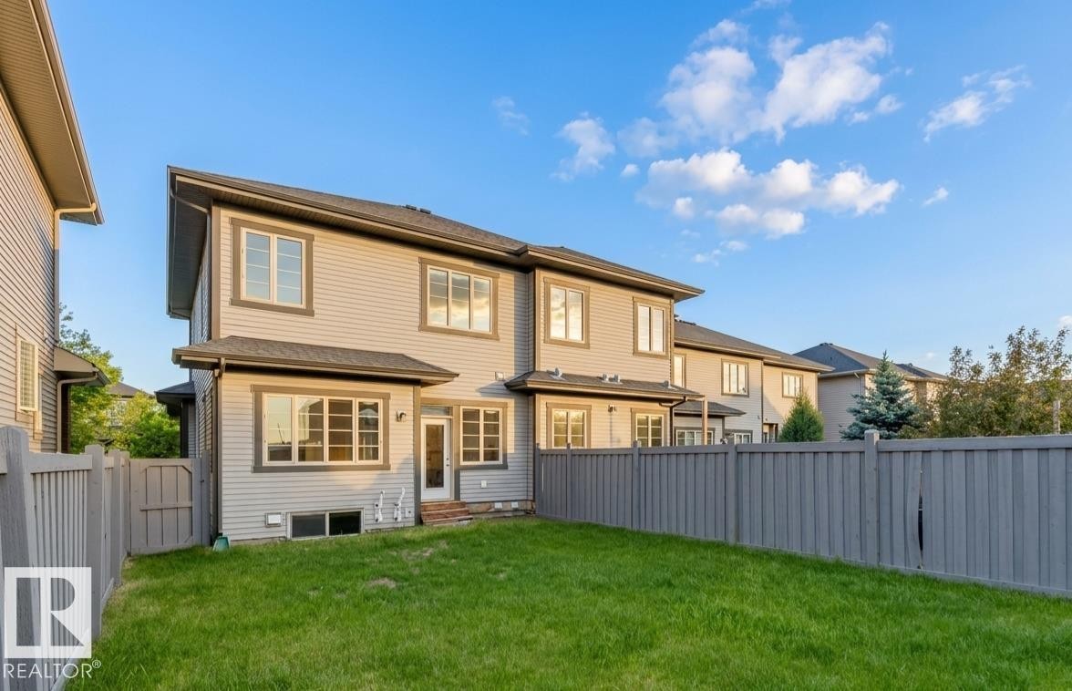 Rear exterior featuring light-colored siding, dark trim, and multiple large windows - 2921 Anderson Crest Sw, Edmonton, AB - Outdoor