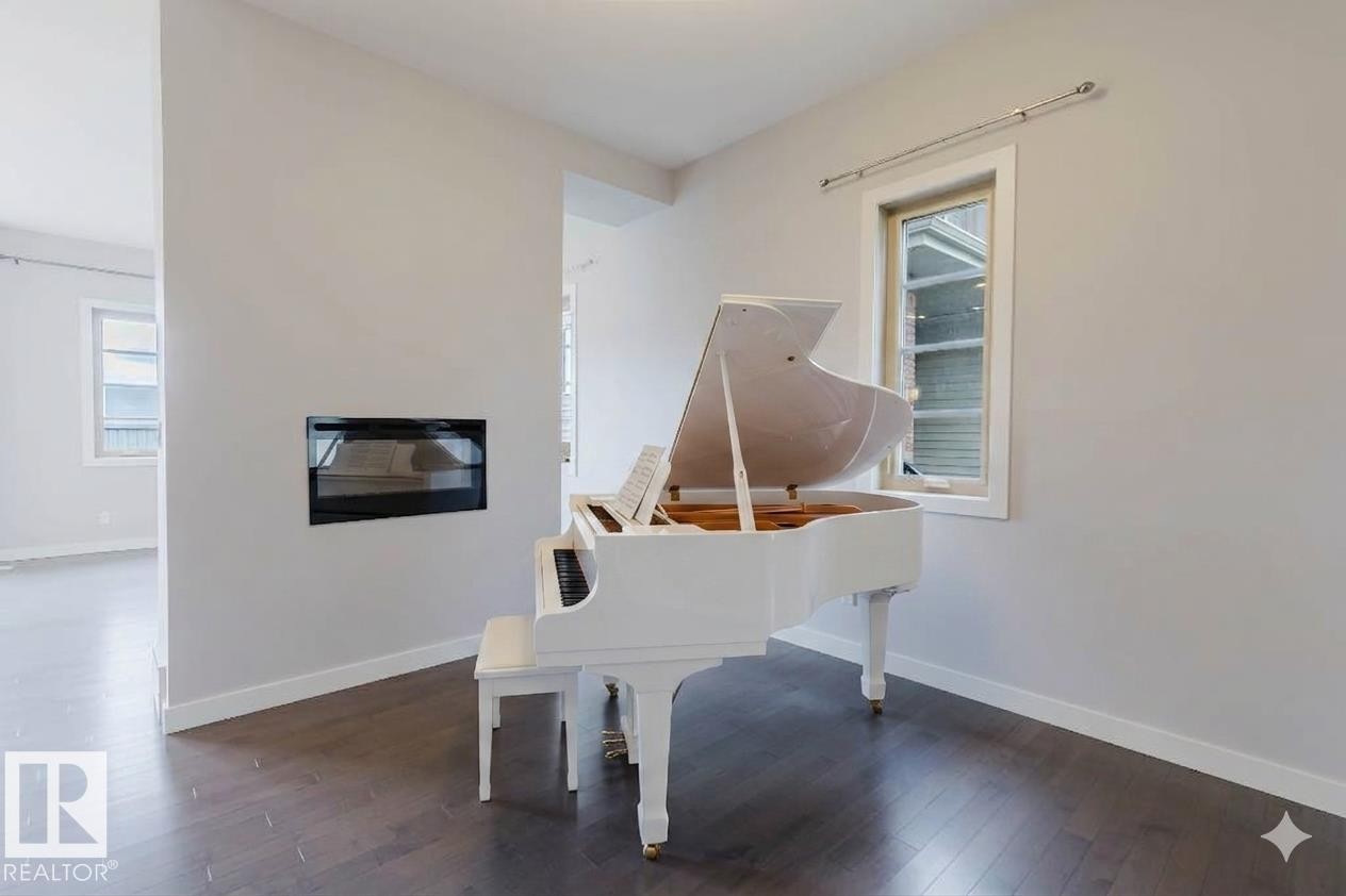 Open-concept interior featuring wood-finish flooring, a built-in linear fireplace, and modern windows with white trim - 2921 Anderson Crest Sw, Edmonton, AB - Indoor With Fireplace