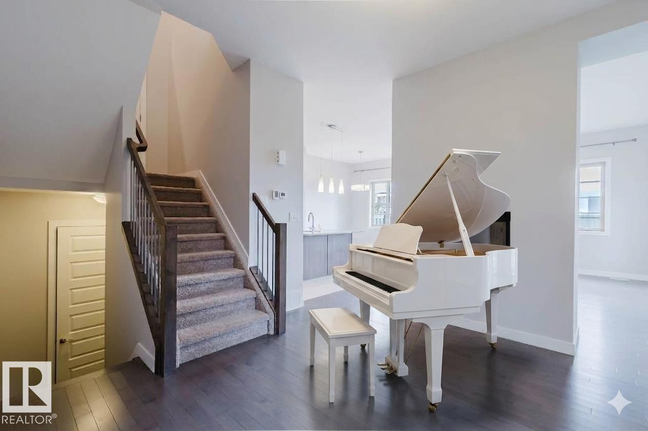 Entry foyer featuring dark wood-finish flooring and a carpeted staircase with dark wood handrails and metal balusters - 2921 Anderson Crest Sw, Edmonton, AB - Indoor Photo Showing Other Room