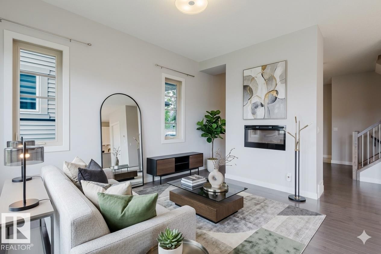 Spacious living area featuring light gray walls, an inset linear fireplace, and wood-finish flooring - 2921 Anderson Crest Sw, Edmonton, AB - Indoor Photo Showing Living Room With Fireplace
