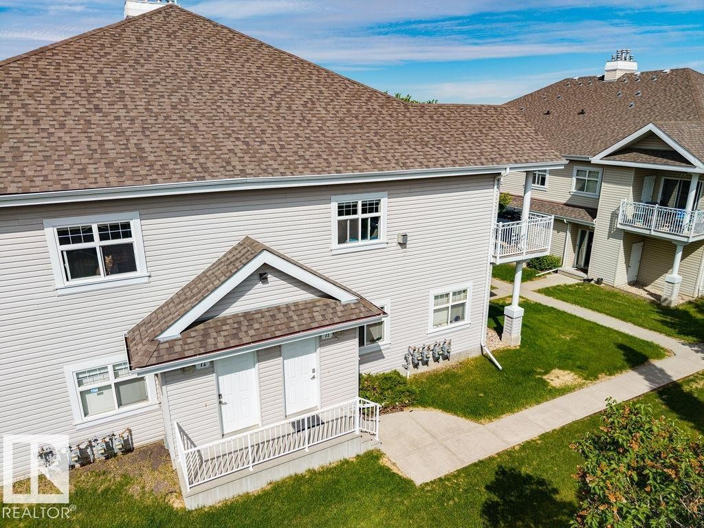 Multi-unit building exterior featuring light-colored horizontal siding and brown shingle roofing - 71 3040 Spence Wynd, Edmonton, AB