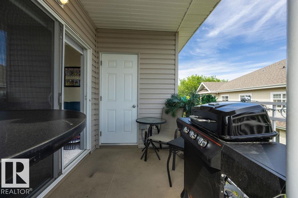 Covered outdoor patio area featuring neutral-toned siding, a sliding glass door, and an exterior door - 71 3040 Spence Wynd, Edmonton, AB